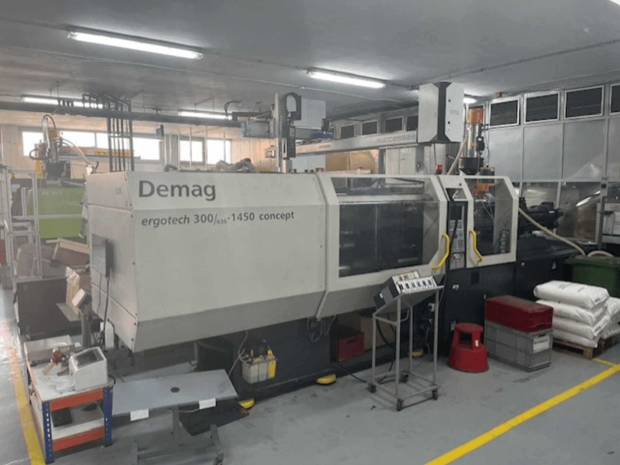 Hydrauliczna wtryskarka Demag ERGOTECH CONCEPT 3000-1450, widok z przodu, z elementami sterującymi i materiałami w pobliżu.