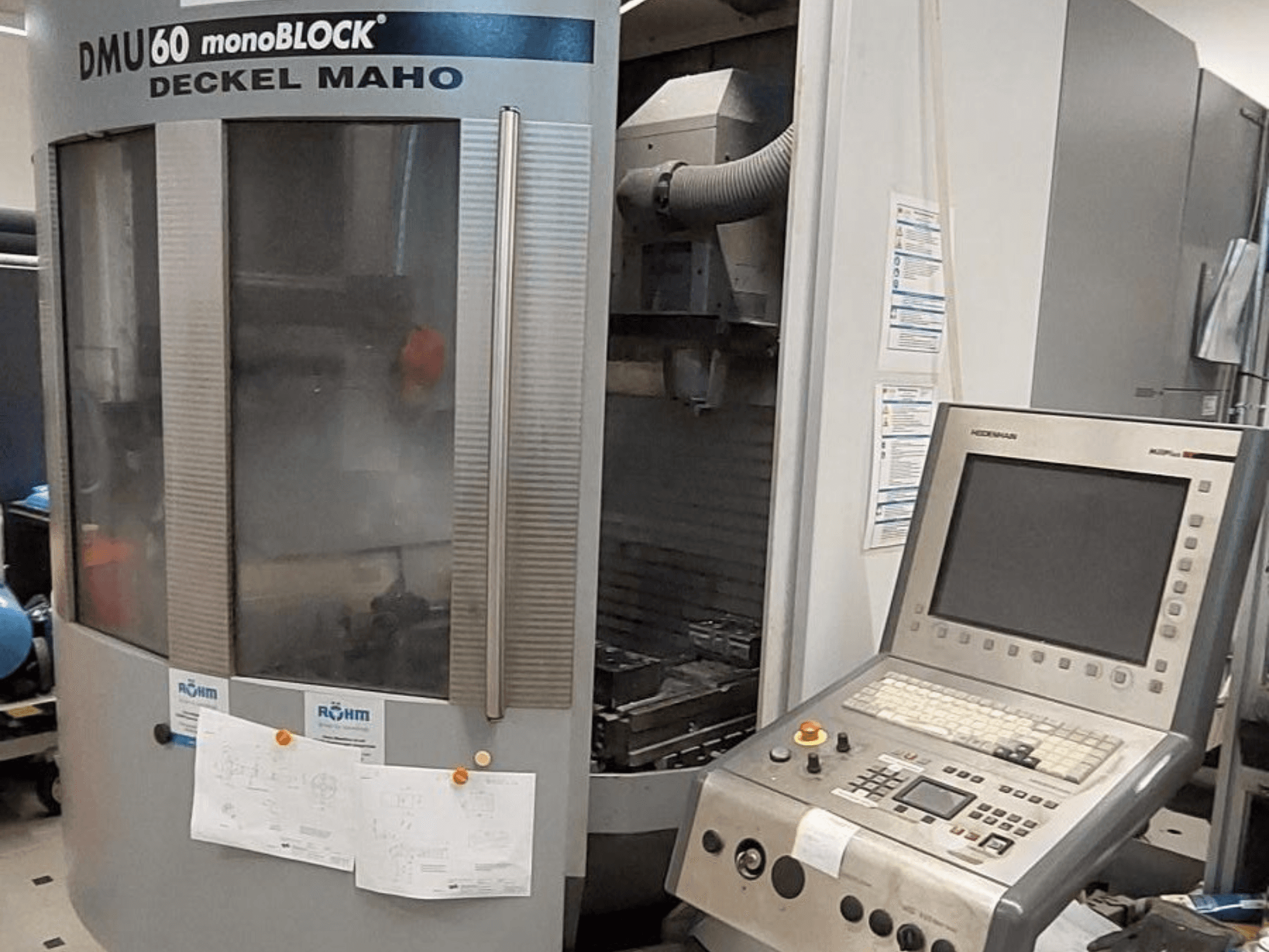 DMU 60 monoBLOCK firmy Deckel Maho, widok z przodu frezarki CNC z panelem sterowania i dołączonymi rysunkami technicznymi.