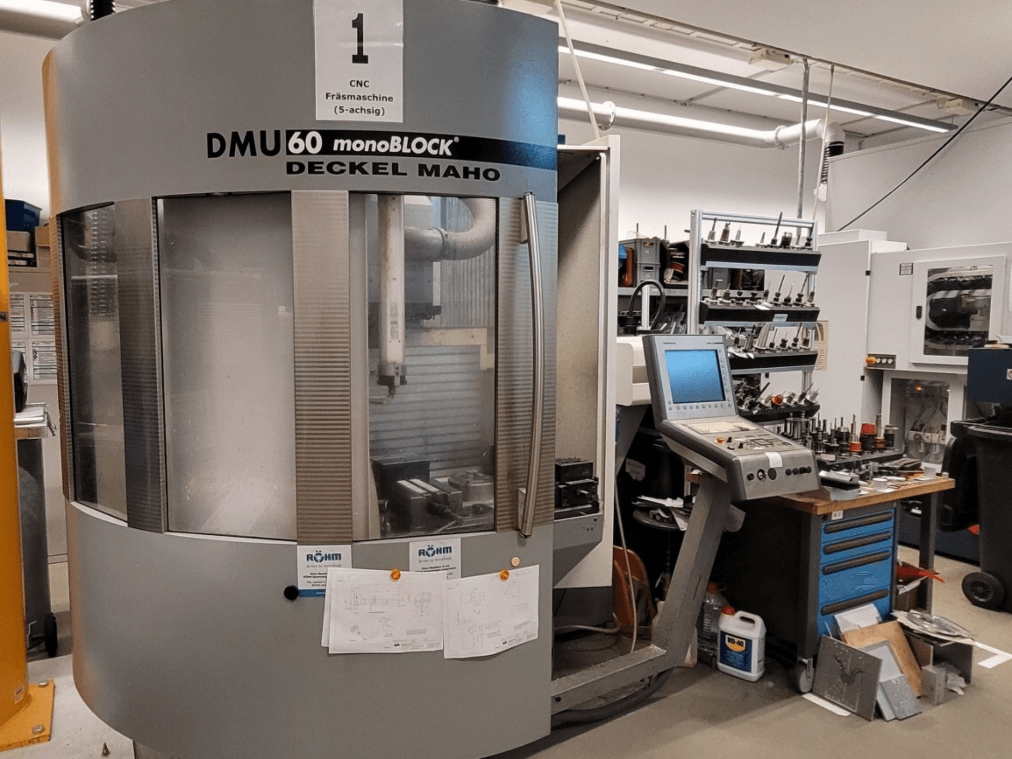 Frezarka CNC DECKEL MAHO DMU 60 monoBLOCK w widoku z przodu, z panelem sterowania i magazynem narzędzi obok.