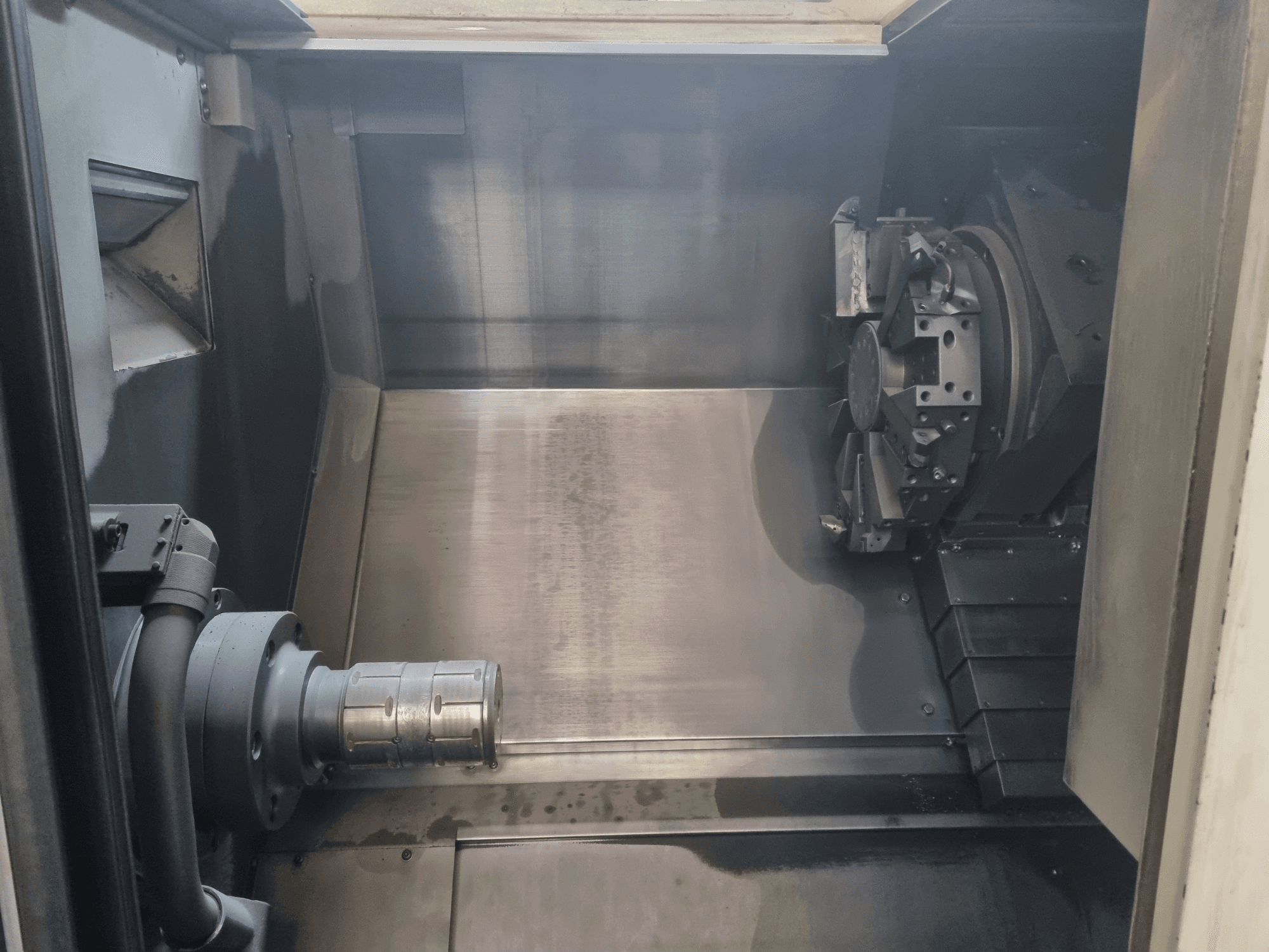 Widok wnętrza maszyny CNC przedstawiający metalowy obszar roboczy, uchwyt narzędziowy i uchwyt; podkreśla precyzję wykonania.