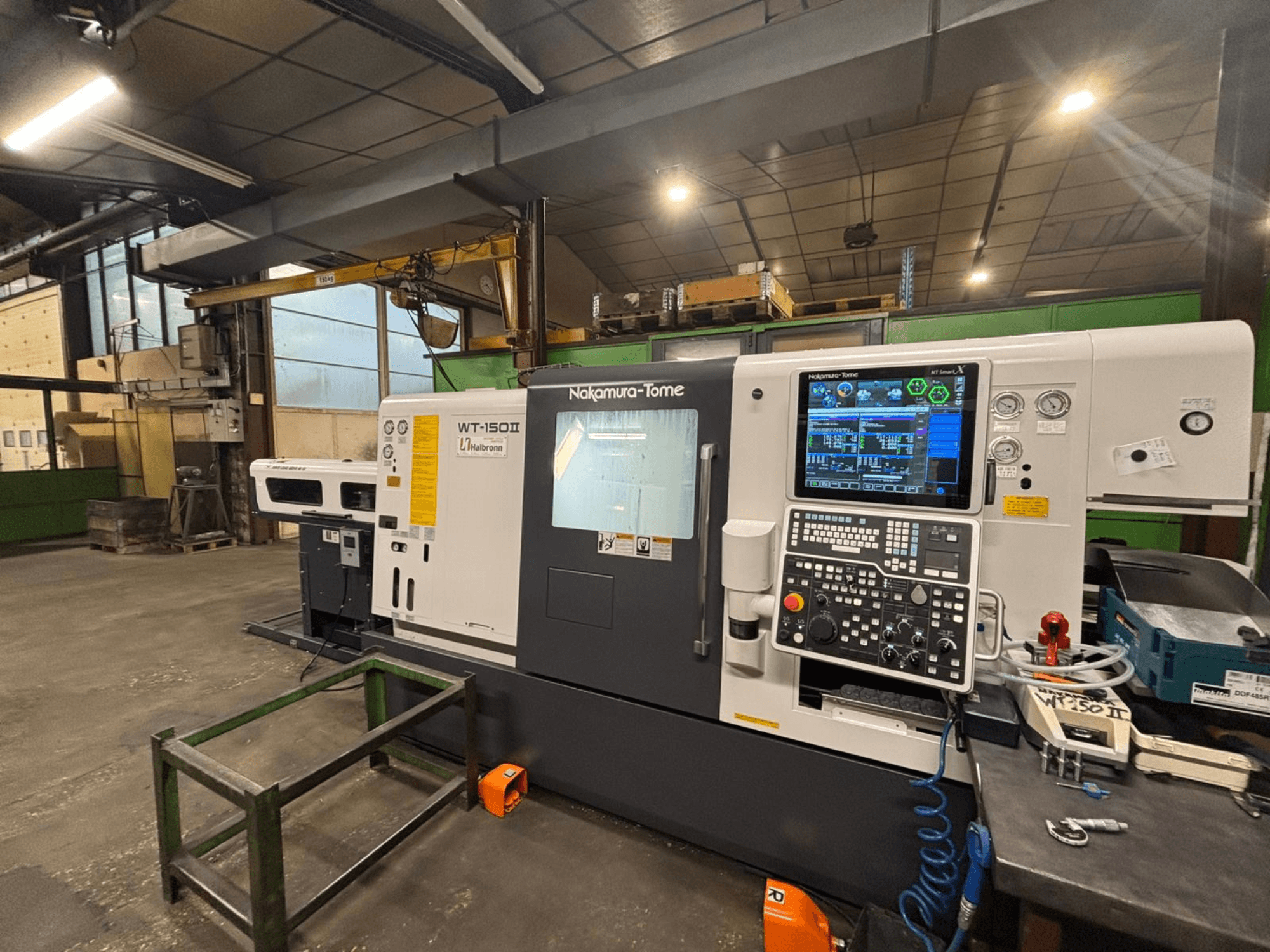 Maszyna Nakamura-Tome WT-150II, widok z przodu, z panelem sterowania i narzędziami widocznymi na stole warsztatowym.