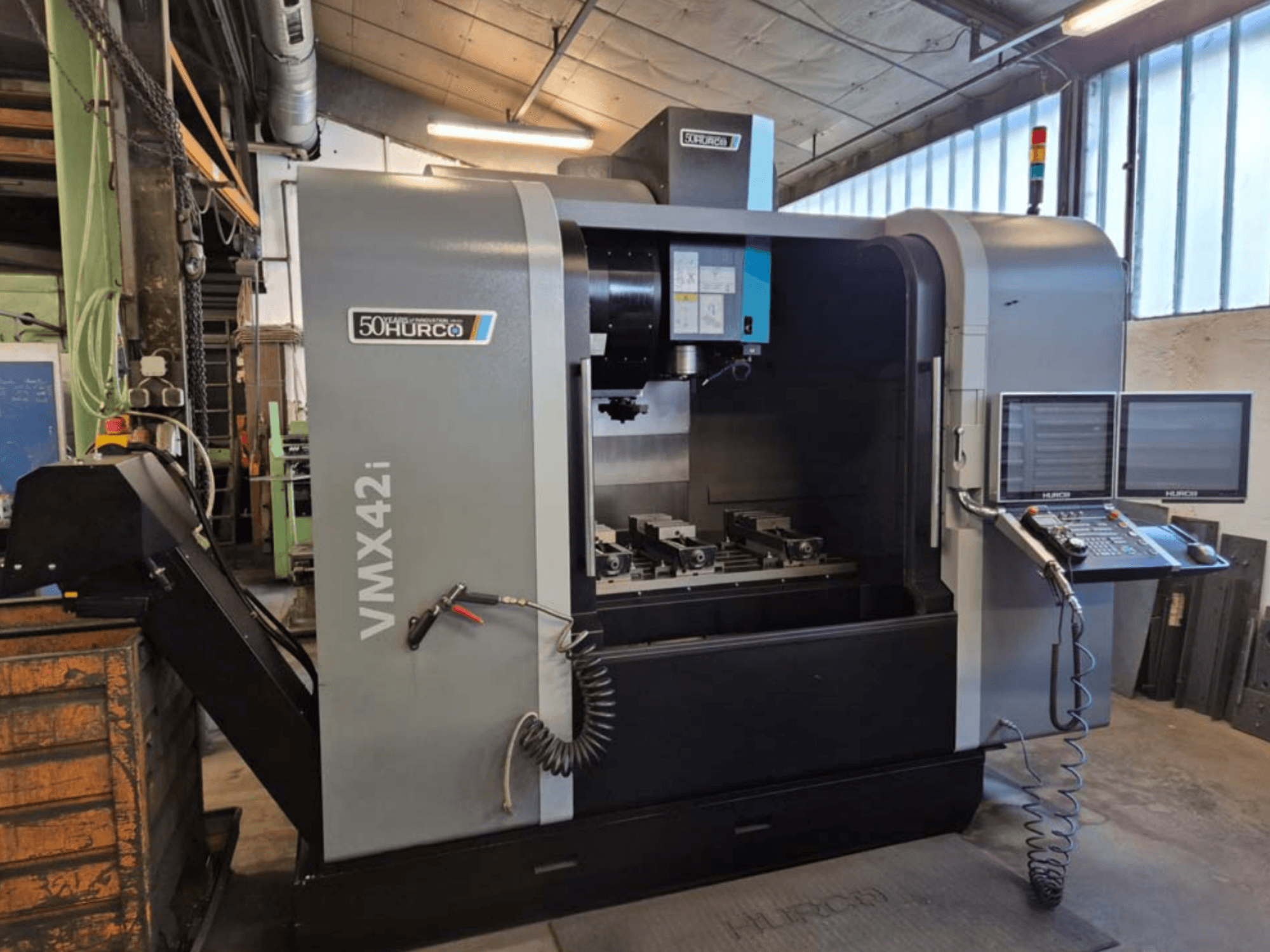 Pionowe centrum obróbcze Hurco VMX 42i, widok z przodu, panel sterowania i obszar roboczy z imadłami.