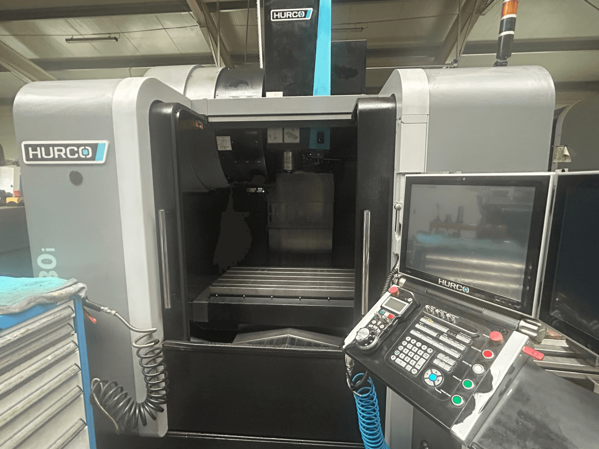 Widok z przodu maszyny CNC Hurco VM30i z panelem sterowania z przyciskami, wyświetlaczem i schowkiem na narzędzia.