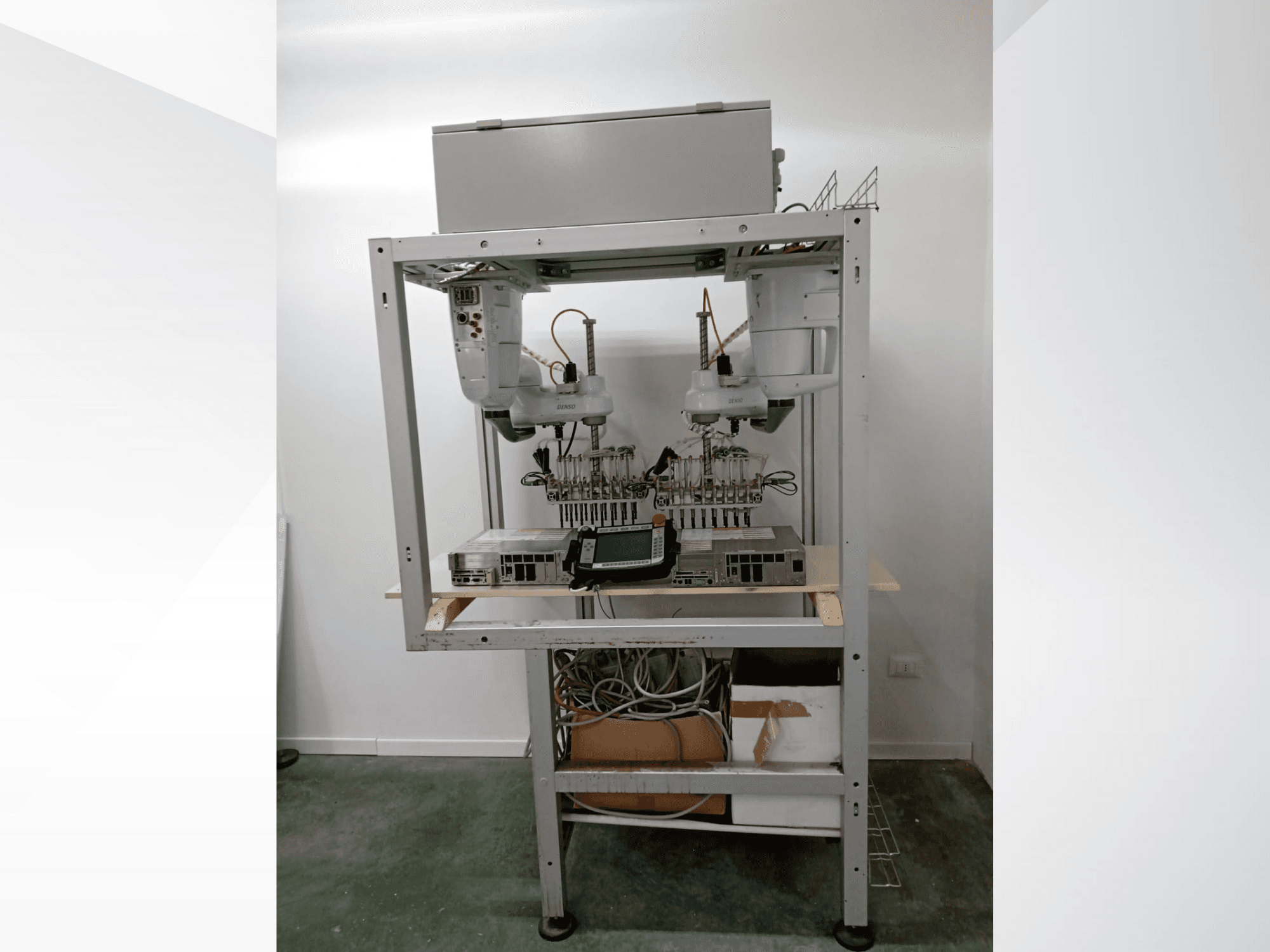 Zautomatyzowana zrobotyzowana stacja robocza z podwójnymi ramionami, wyświetlaczem i elektroniką na metalowej ramie, widok z przodu, zaawansowana konfiguracja technologiczna.