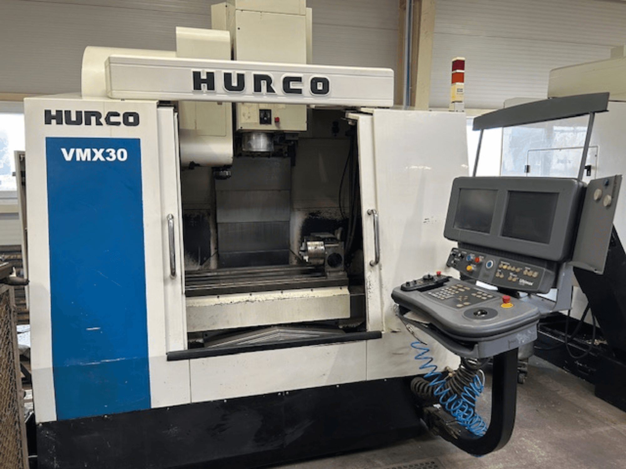 Frezarka CNC Hurco VMX30 w warsztacie, widok z przodu; posiada panel sterowania z dwoma ekranami i przyciskami operacyjnymi.