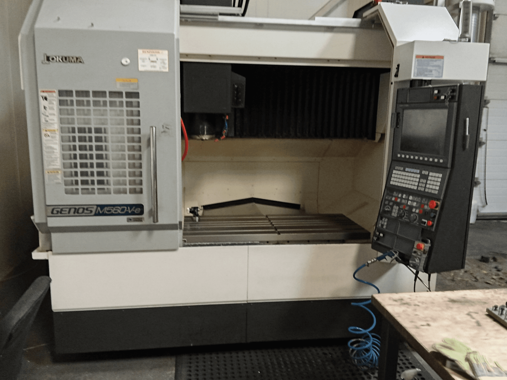 Okuma GENOS M560-V, widok z przodu pionowego centrum obróbczego z panelem sterowania, interfejsem CNC i widocznym obszarem cięcia.
