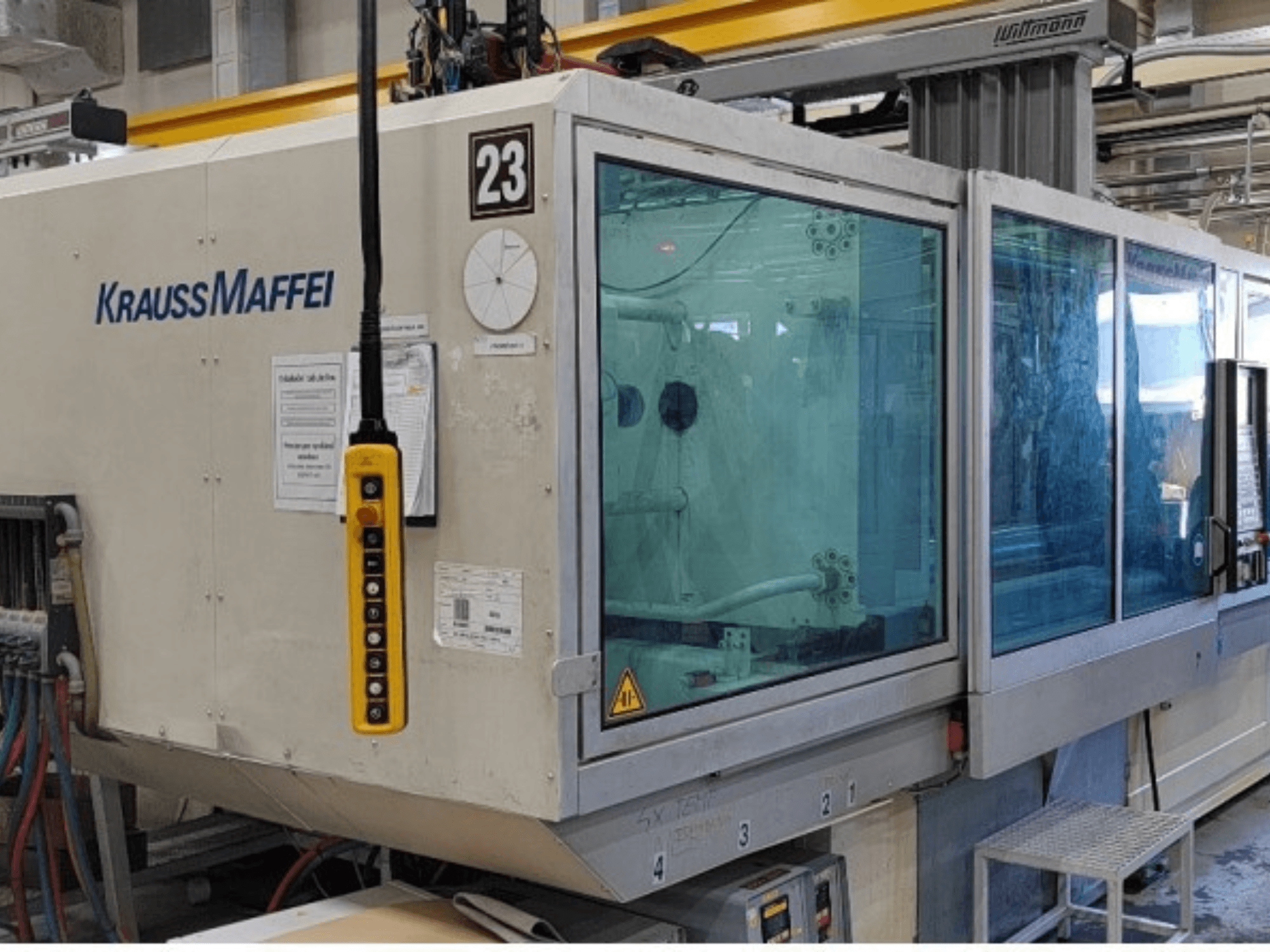 Hydrauliczna wtryskarka Krauss Maffei KM 350-1900 C2 – widok z przodu przedstawiający panel sterowania i przezroczystą osłonę zabezpieczającą.
