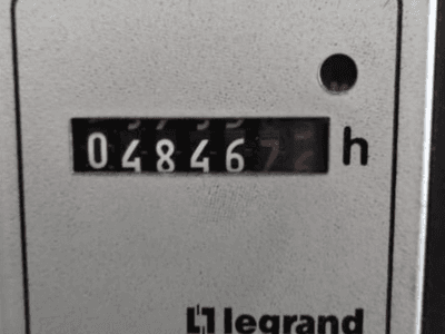 Licznik godzin Legrand 048467.6, widok z przodu z czerwonym wskaźnikiem i czarnymi cyframi na teksturowanym jasnym tle.