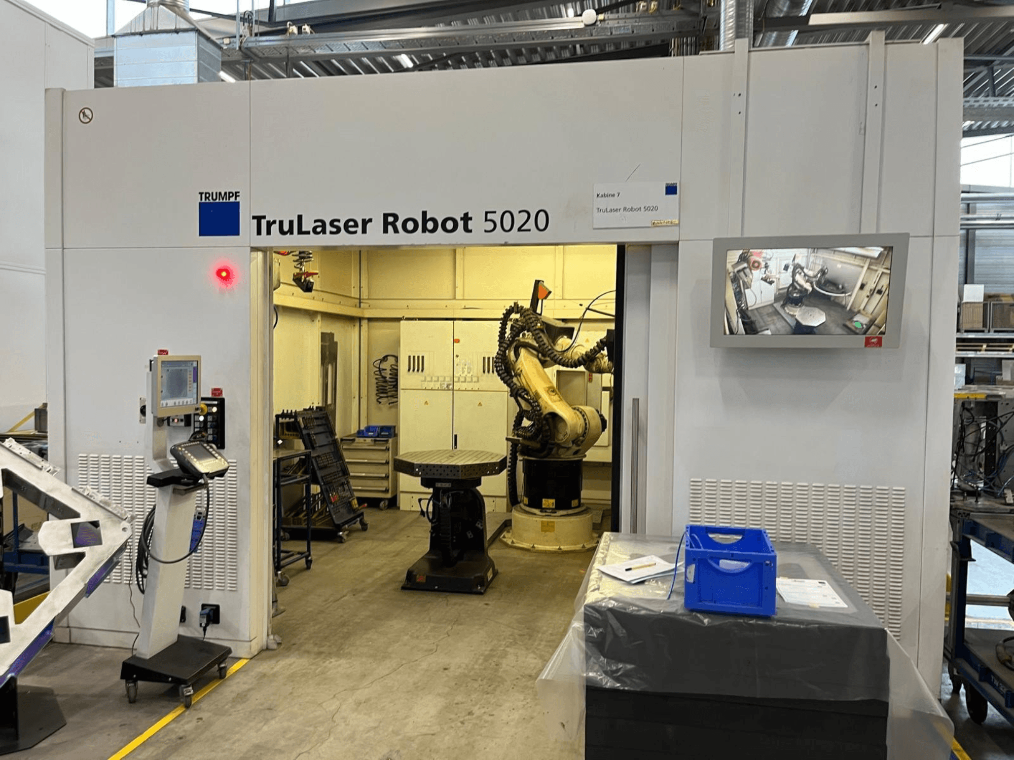 Maszyna TRUMPF TruLaser Robot 5020 w środowisku przemysłowym, wyposażona w panel sterowania, ramię robota oraz monitor wyświetlający przebieg operacji.
