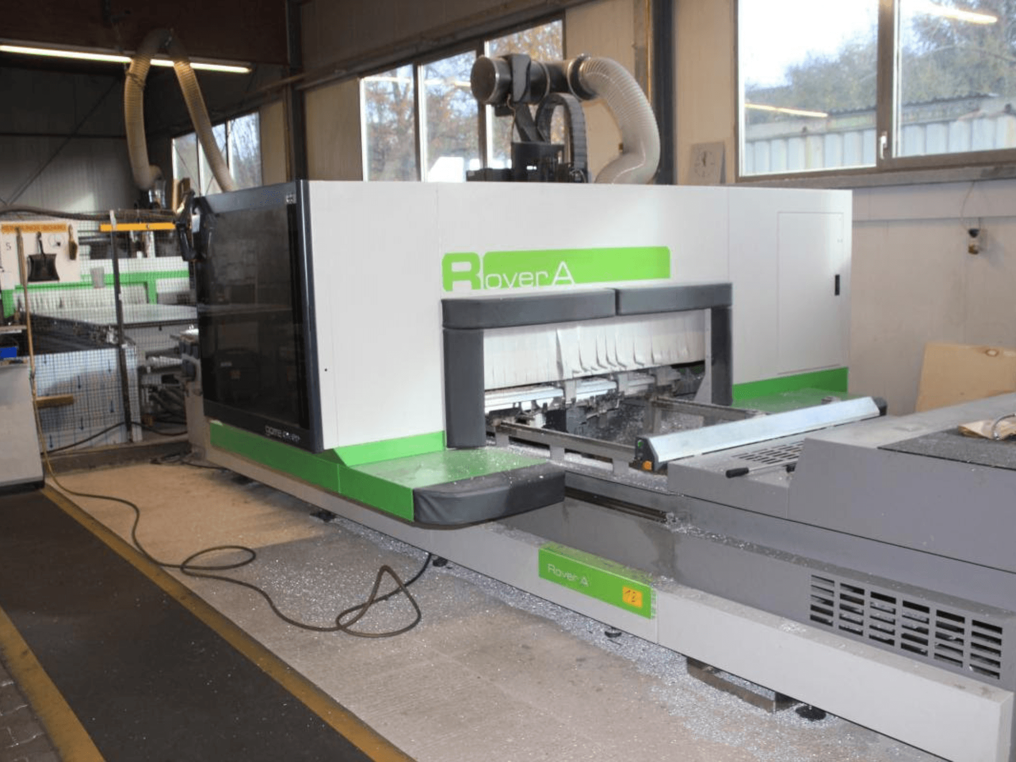 Frezarka CNC BIESSE Rover A 1232, widok z boku pokazujący obszar cięcia i panel sterowania w warunkach przemysłowych.
