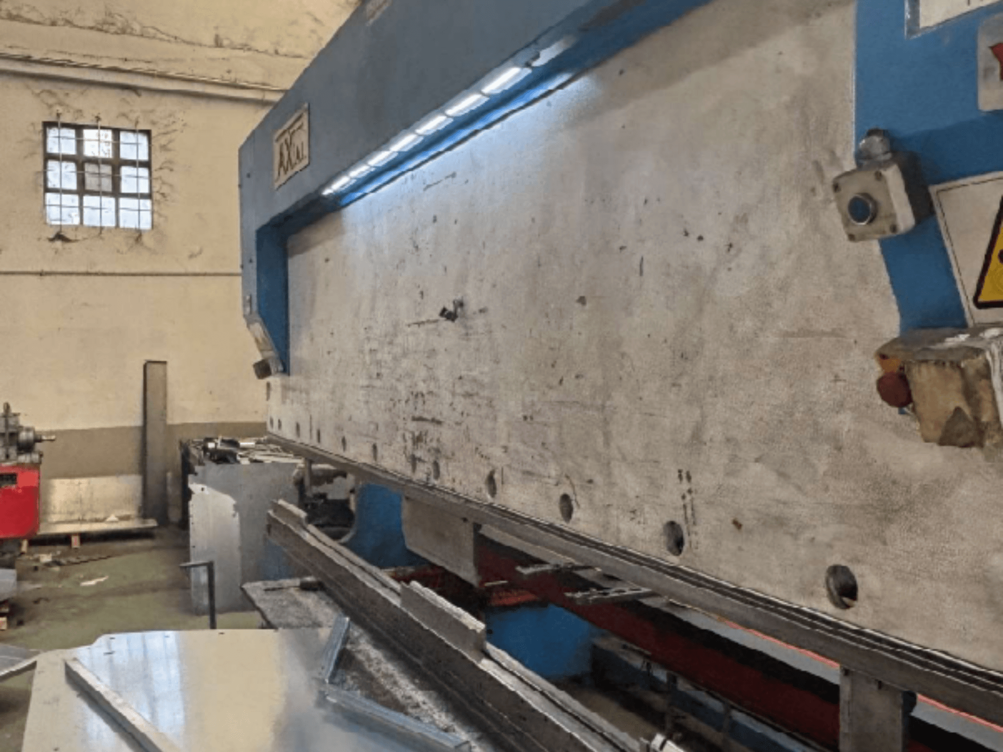 System obsługi palet Axial PHS-W-124 w warsztacie, widok z boku pokazujący powierzchnię roboczą i szczegóły panelu sterowania.