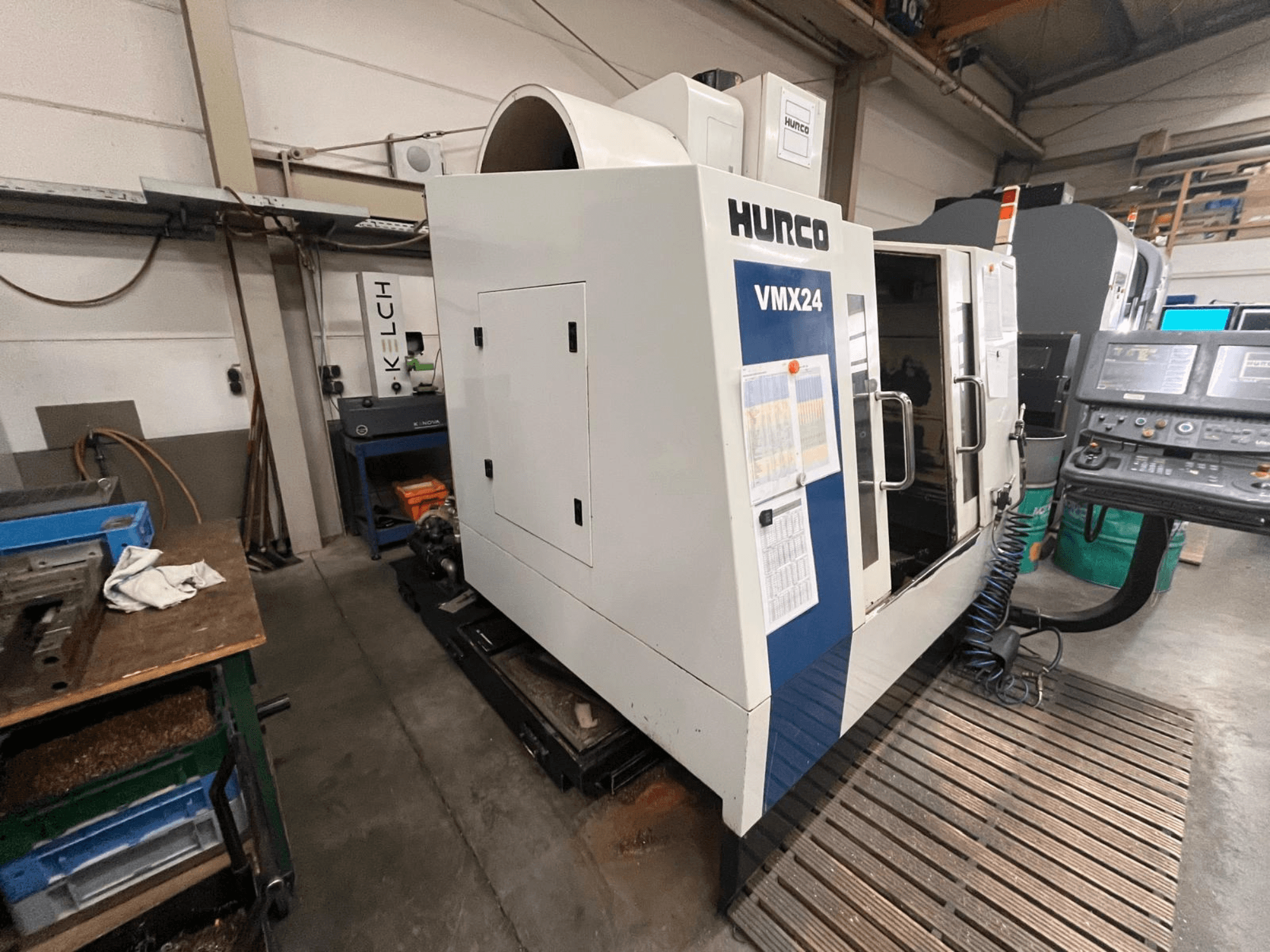 Maszyna CNC Hurco VMX24 w warsztacie, widok z przodu; posiada panel sterowania i otwarte drzwi dostępowe.