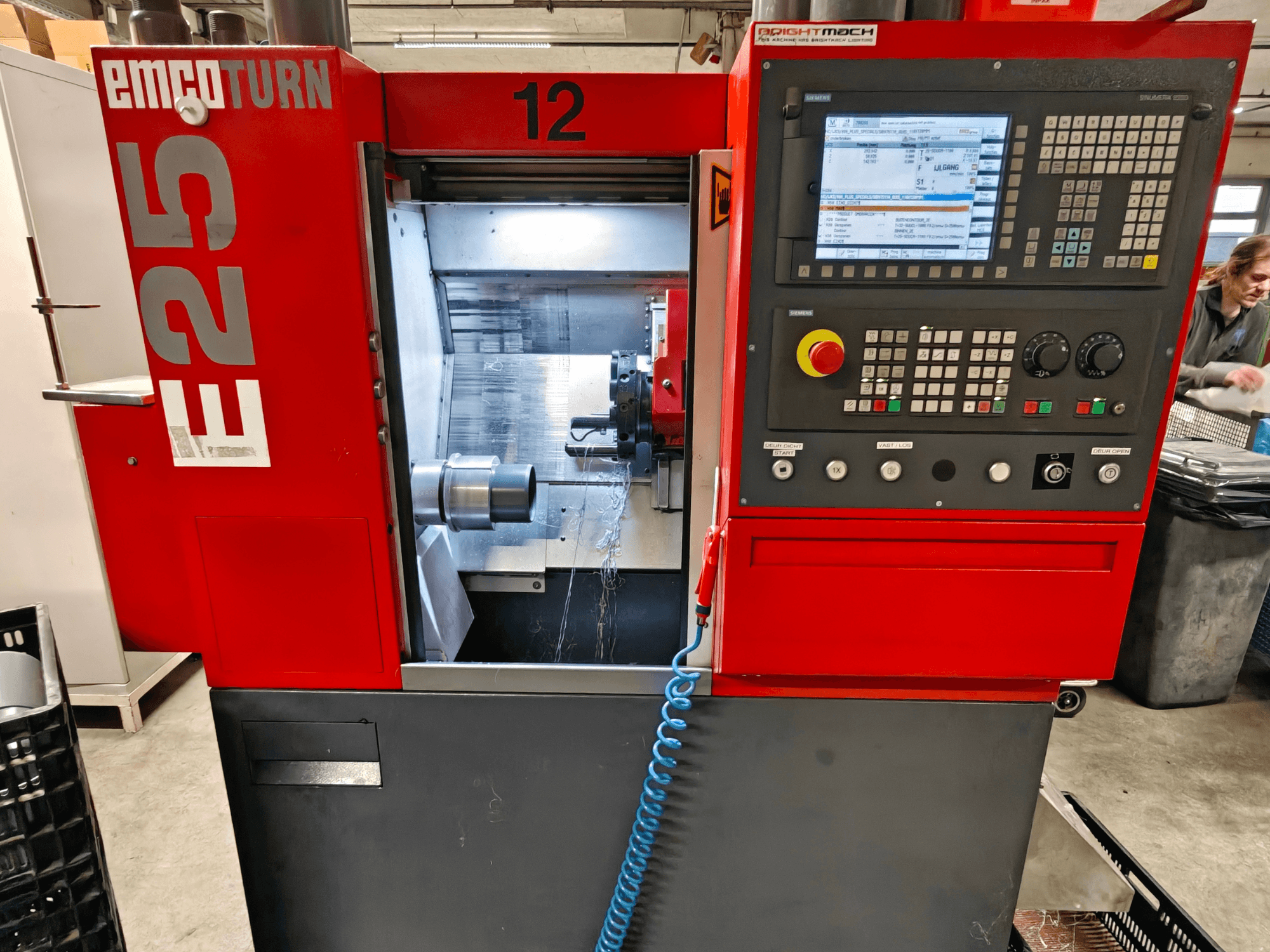 Widok z przodu maszyny EMCO TURN E25 z panelem sterowania, uchwytem narzędziowym i obszarem wewnętrznym z widocznym narzędziem tnącym.
