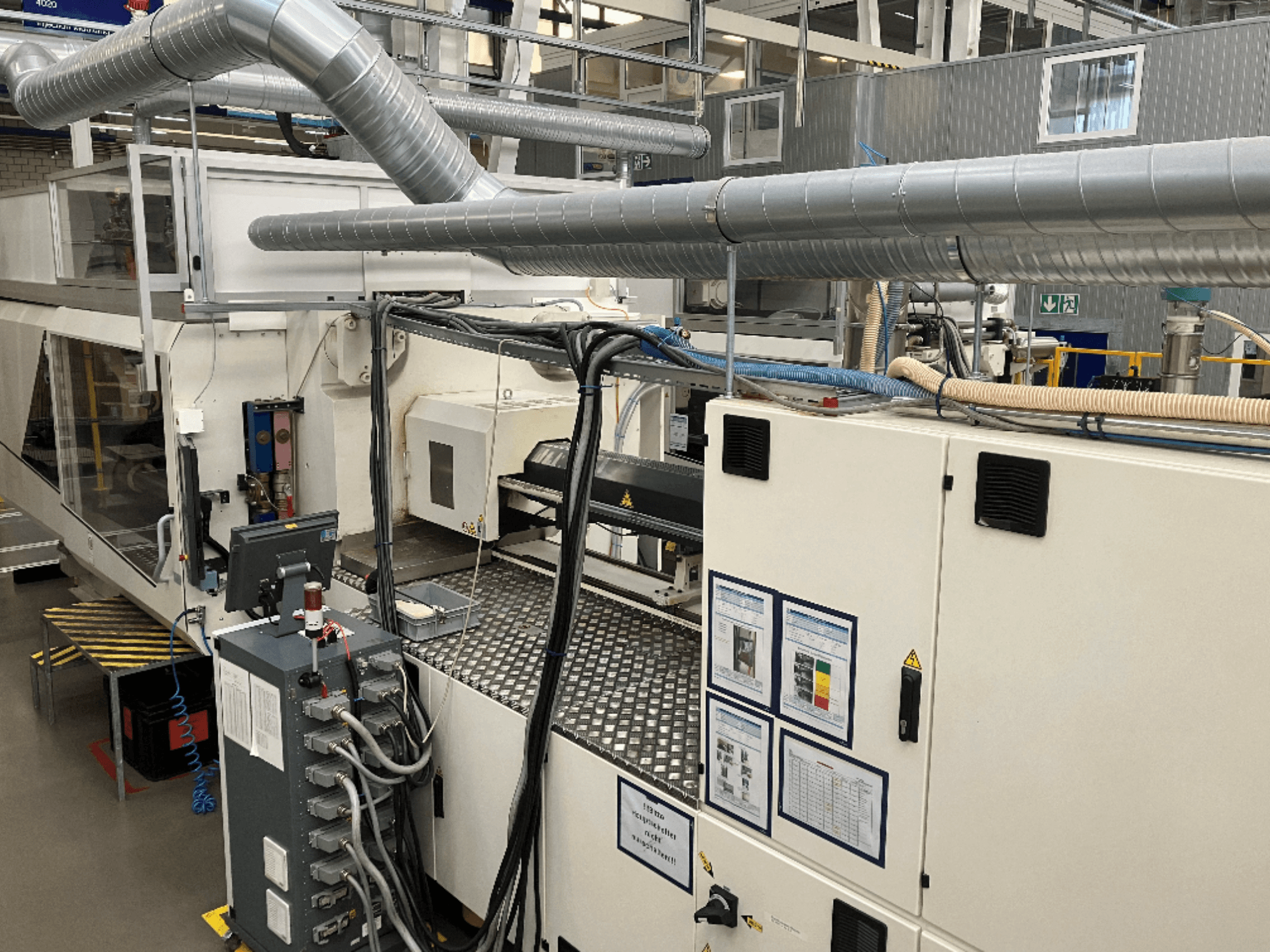 Maszyny przemysłowe z rozbudowanym orurowaniem, panelem sterowania i instrukcjami obsługi, oglądane z perspektywy z góry na dół.