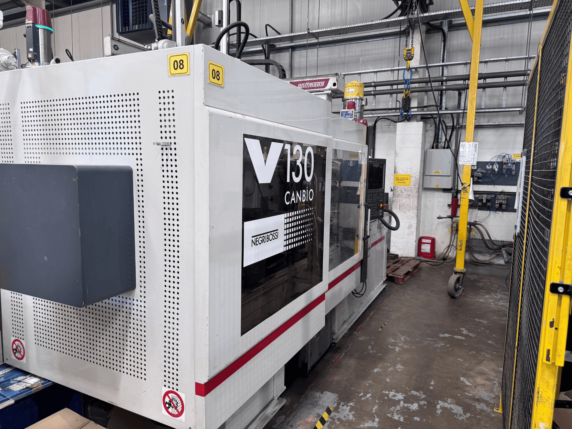 Hydrauliczna wtryskarka Negri Bossi 1300H-400, widok z boku, z panelem sterowania i oznakowaniem bezpieczeństwa.