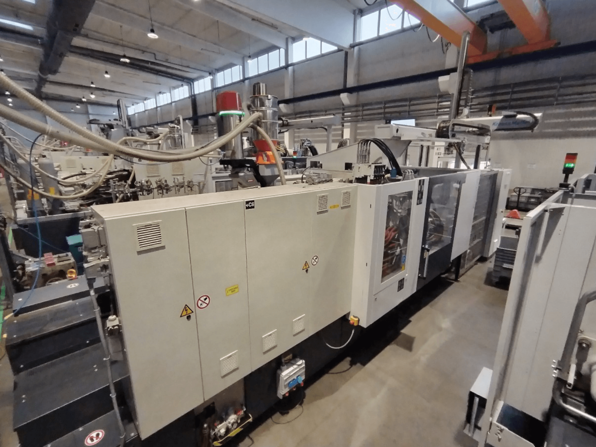 Przemysłowa wtryskarka pokazana z boku, z panelem sterowania i ostrzeżeniami dotyczącymi bezpieczeństwa. Marka: Nieznany.