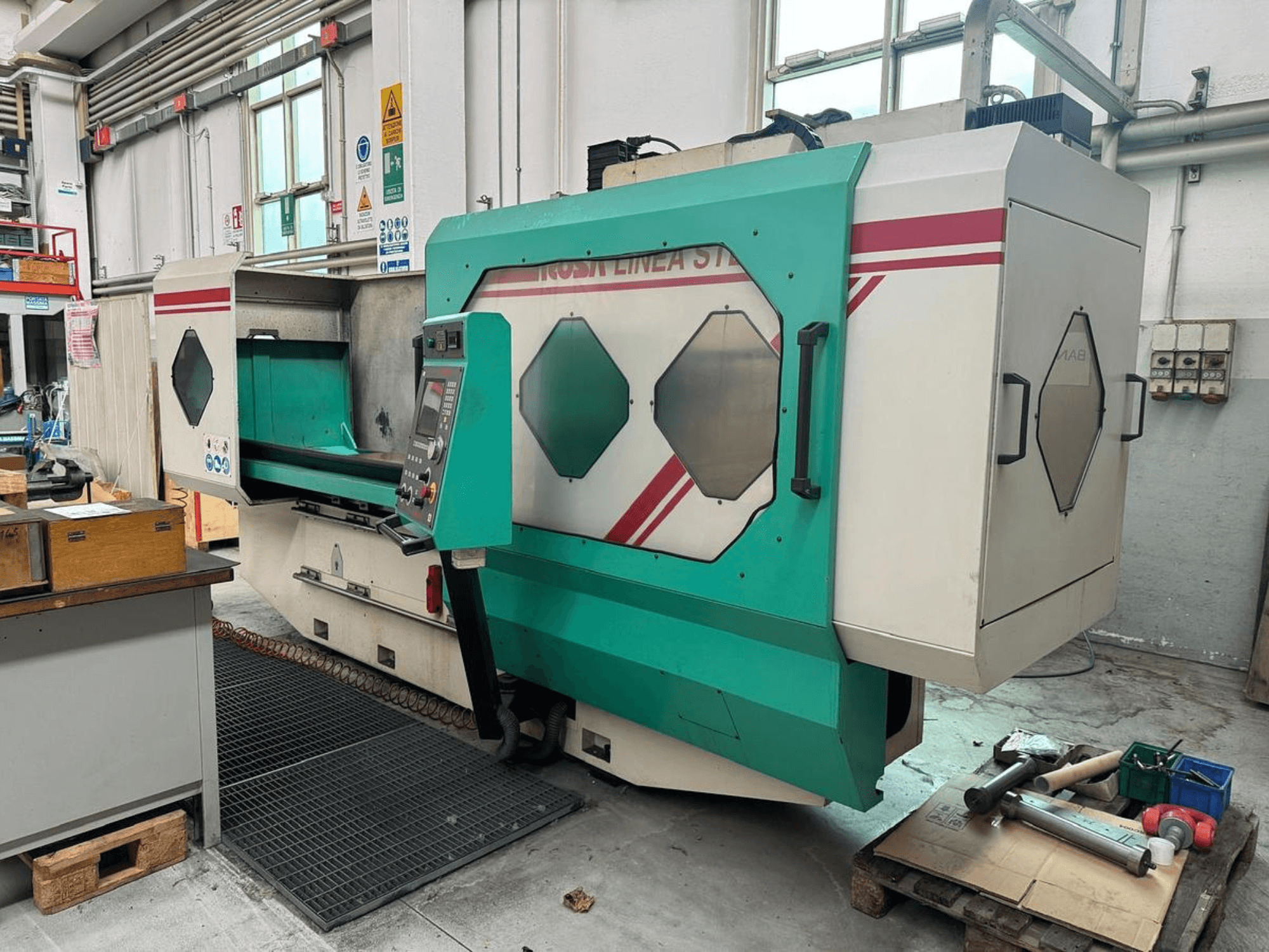 Zielono-biała precyzyjna maszyna, widok z przodu, z panelem sterowania, obszarem roboczym i narzędziami na palecie. Marka: BAMB.