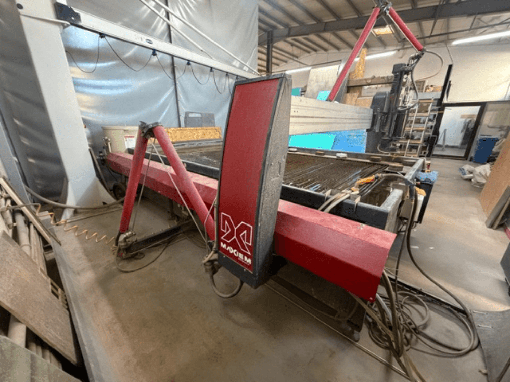 Czerwona maszyna do cięcia strumieniem wody marki X, widziana z boku, pokazująca elementy mechaniczne i szczegóły orurowania.