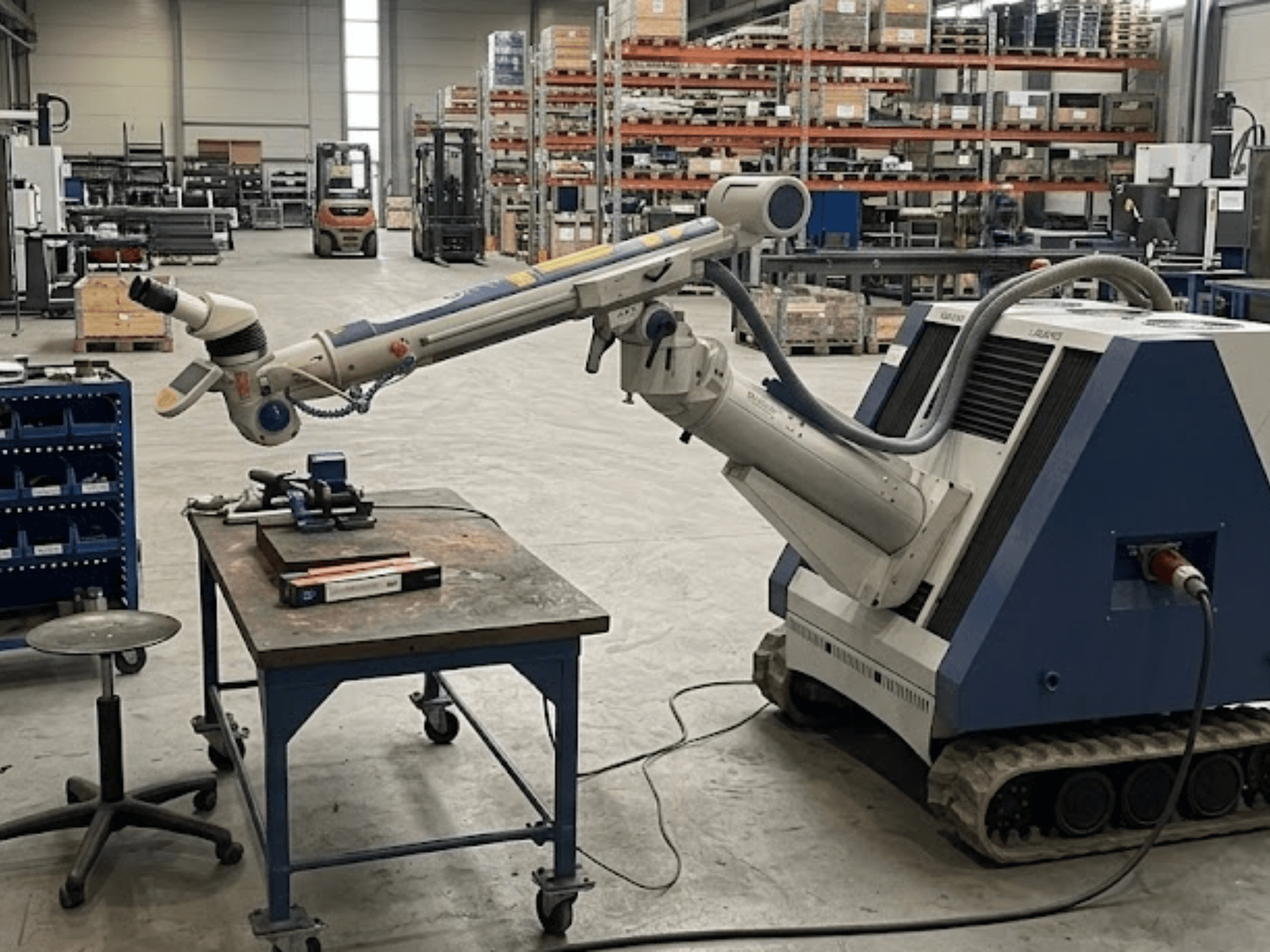 Obrabiarka ALPHA LASER ALFlak300 M w warsztacie z ramieniem robota; widok z przodu ukazujący precyzyjne ustawienie na stole roboczym.