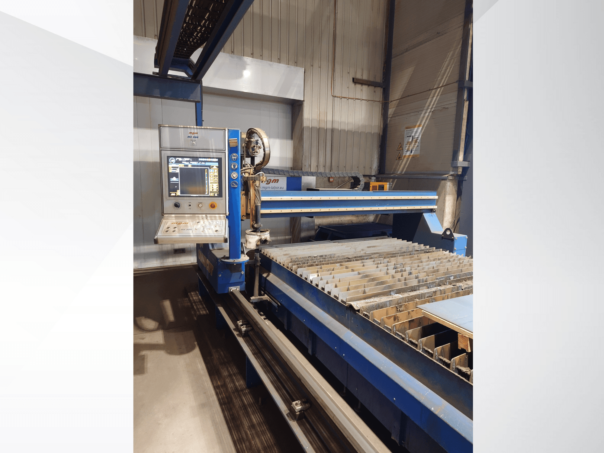 Maszyna do cięcia CNC firmy PlasmaCam, widok z przodu przedstawiający panel sterowania i łóżko do cięcia metalu z listwami.