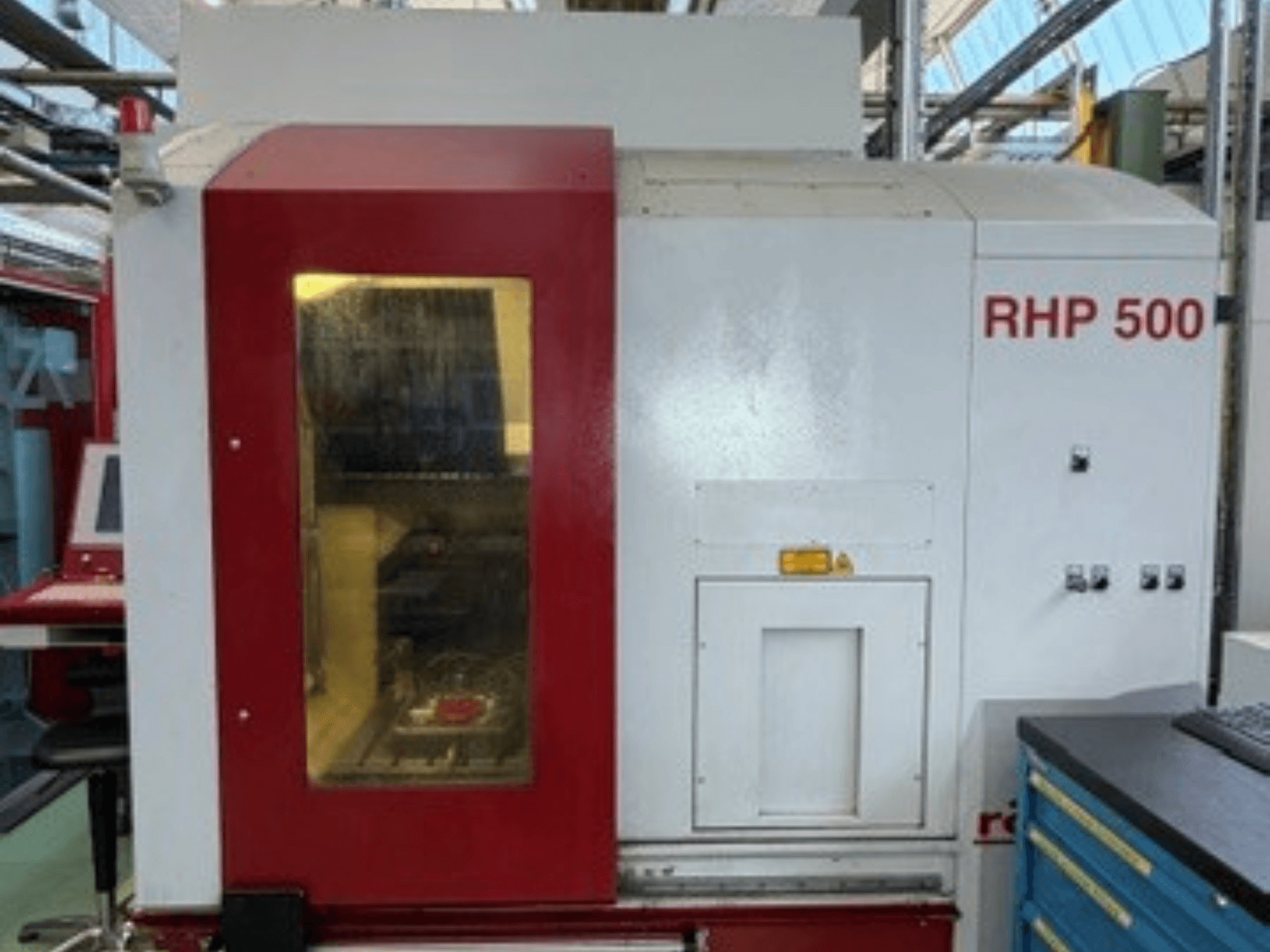 Pionowe centrum obróbcze Röders TEC RHP 500, widok z przodu, przedstawiający panel sterowania oraz przezroczyste okienko, przez które widać wnętrze urządzenia.