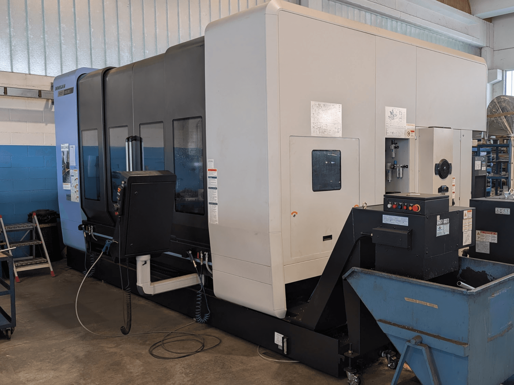 Pionowe centrum obróbcze DOOSAN VCF850LSR-II widziane z boku, z widocznym panelem sterowania, układem chłodzenia oraz solidną konstrukcją.