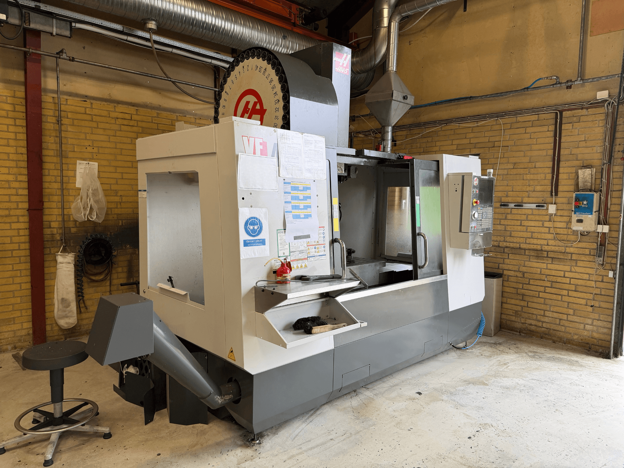 Pionowe centrum obróbcze HAAS VF-4, widok z przodu; w tle widoczny jest panel sterowania, uchwyt narzędziowy oraz konfiguracja produkcyjna.