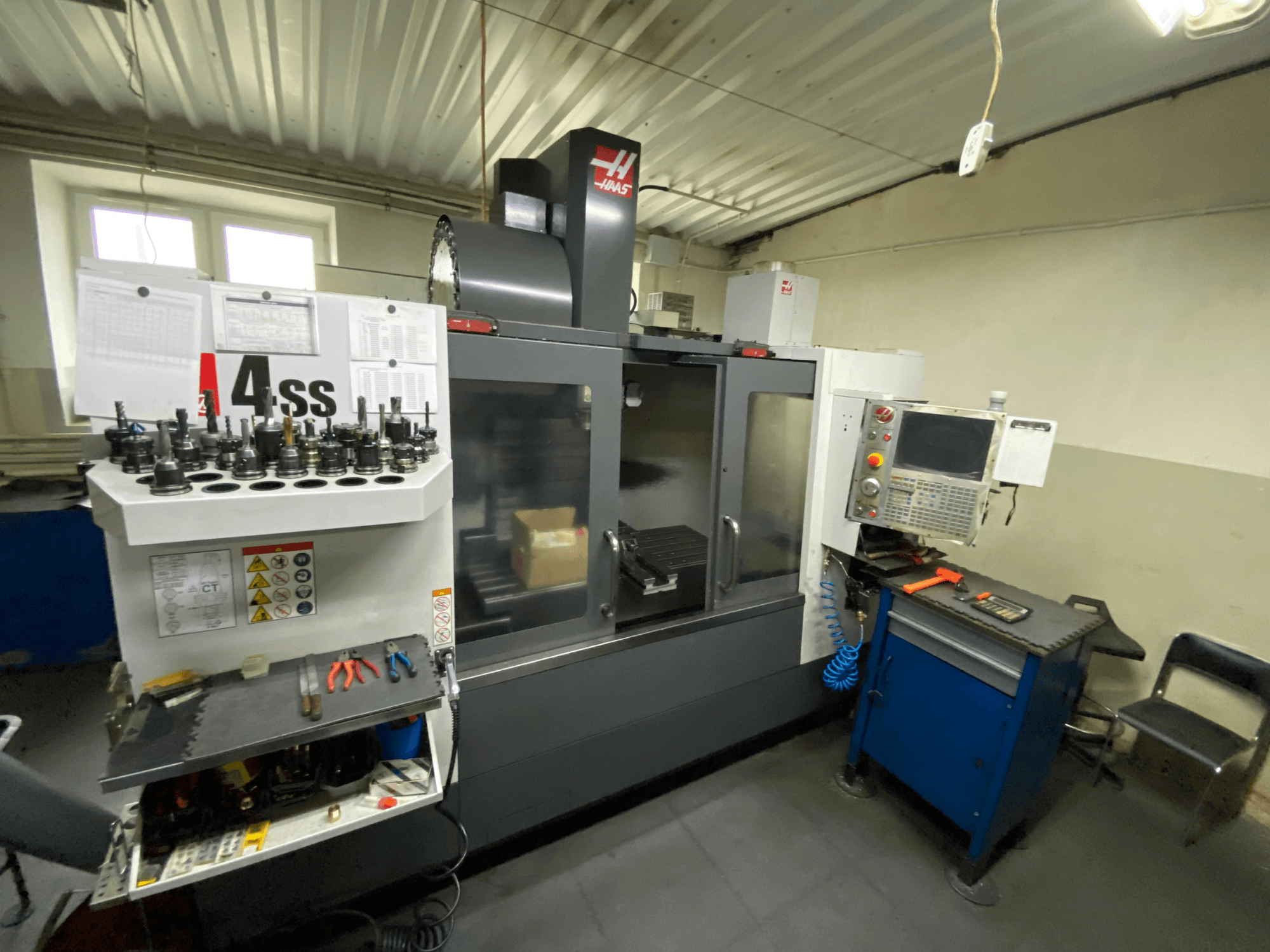 Pionowe centrum obróbcze Haas VF-4SS, widok z przodu z uchwytami narzędziowymi i panelem sterowania. Widoczne są wybrane narzędzia i obszar roboczy.