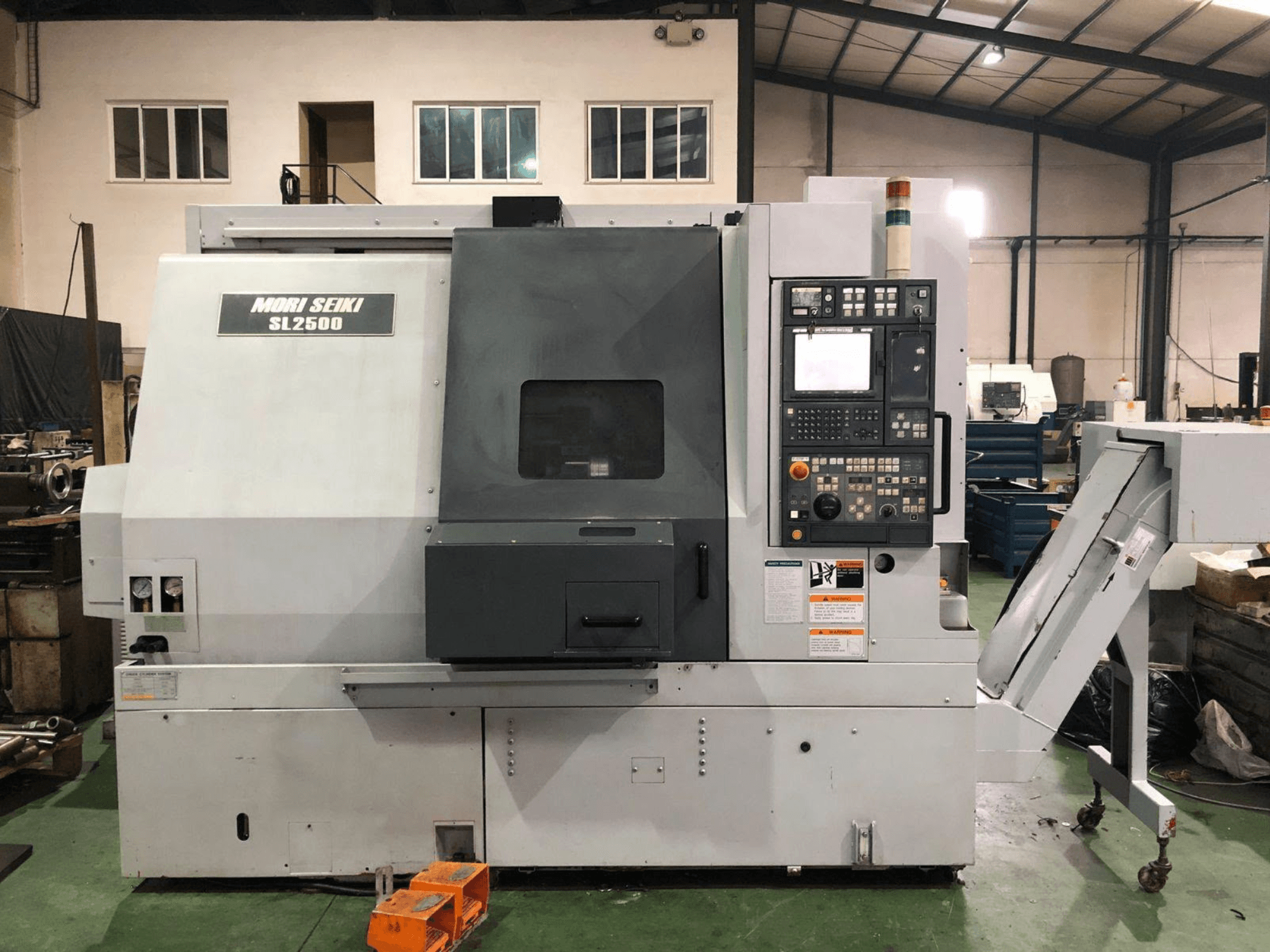 Centrum frezarsko-toczarskie DMG Mori Seiki SL 2500 Y, widok z boku z widocznym panelem sterowania i przenośnikiem wiórów.