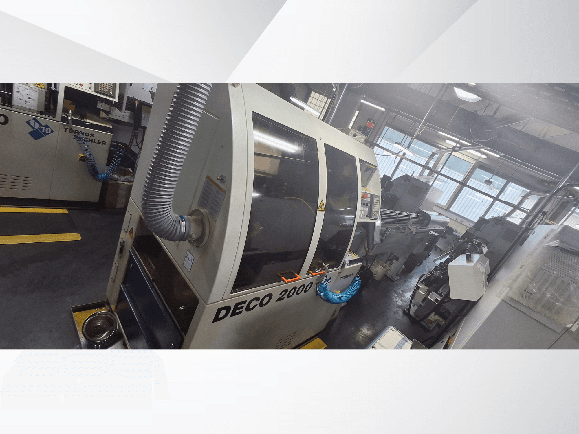 Maszyna CNC DECO 2000 w warsztacie, widok z przodu, z wężem wentylacyjnym i panelem sterowania, przeznaczona do precyzyjnej obróbki.