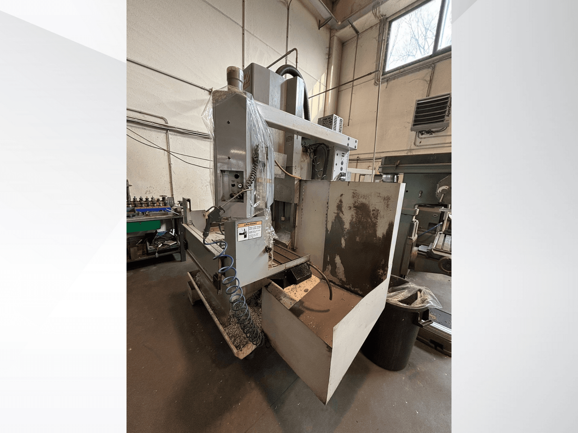 Frezarka pionowa z osłoną ochronną, widok z boku; widoczny wąż chłodziwa i panel sterowania. Idealna do obróbki skrawaniem.