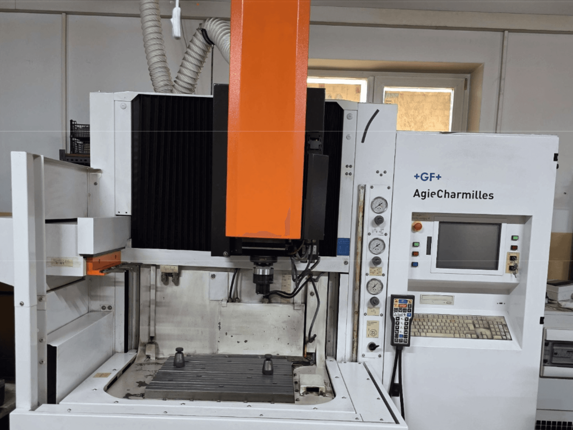 Centrum obróbcze AgieCharmilles w widoku z przodu z dużym pomarańczowym wrzecionem, panelem sterowania i widocznym stołem roboczym.