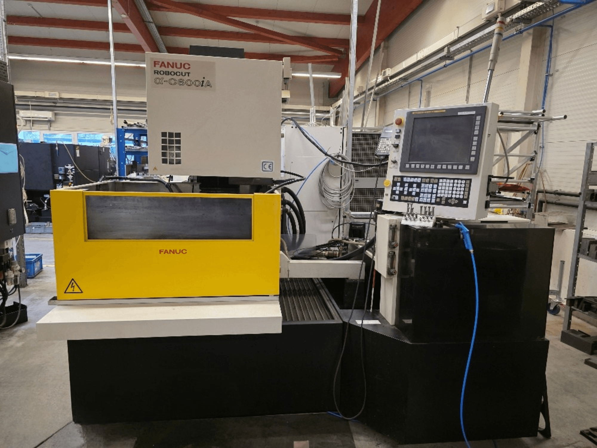 Wycinarka drutowa FANUC Robocut α-C600iA, widok z przodu, z żółtym panelem sterowania i wyświetlaczem cyfrowym.
