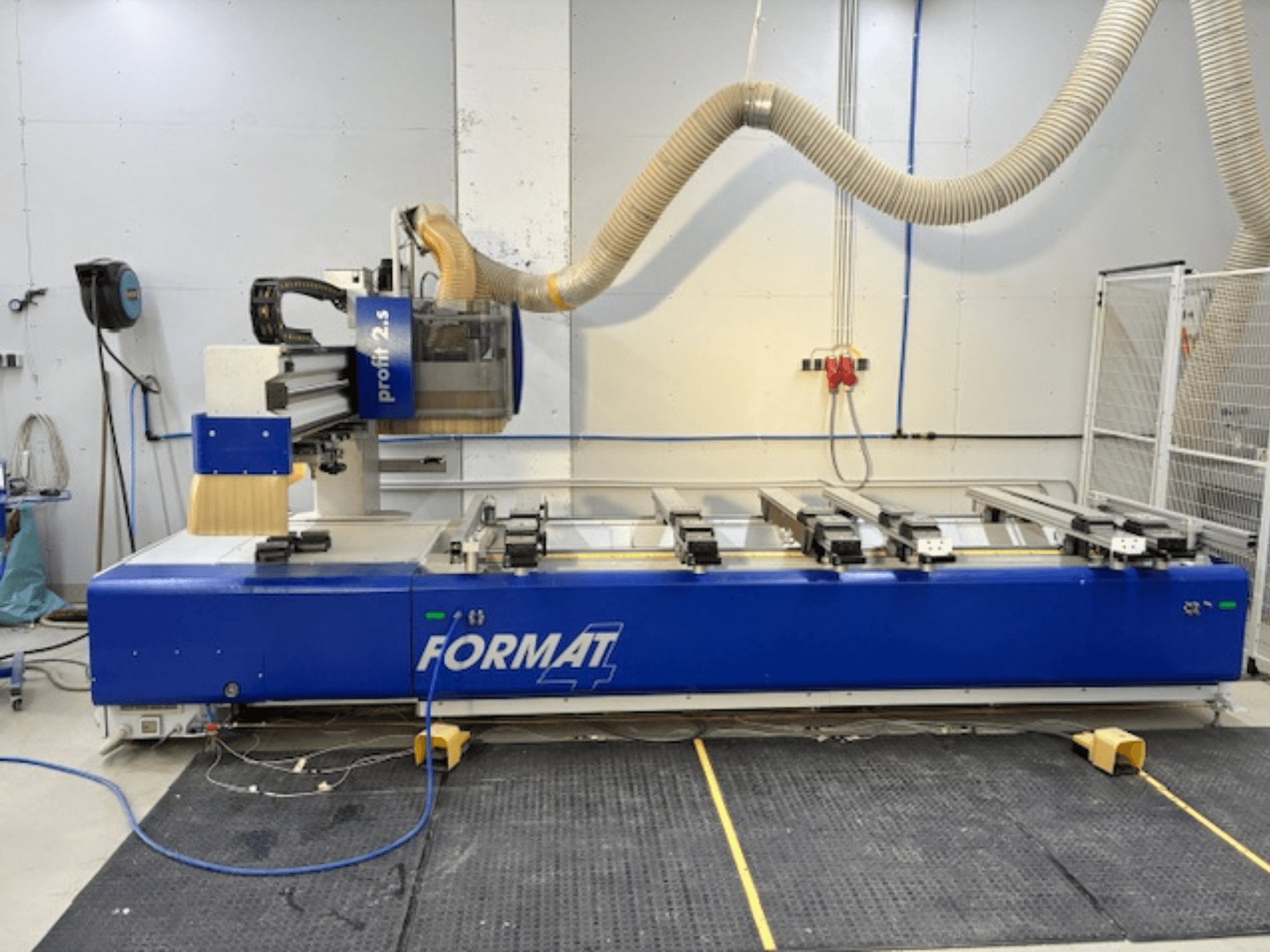 Frezarka CNC Blue FORMAT 4, model Profit 2.5, widok z boku pokazujący obszar cięcia i system odsysania pyłu, na gumowej macie.
