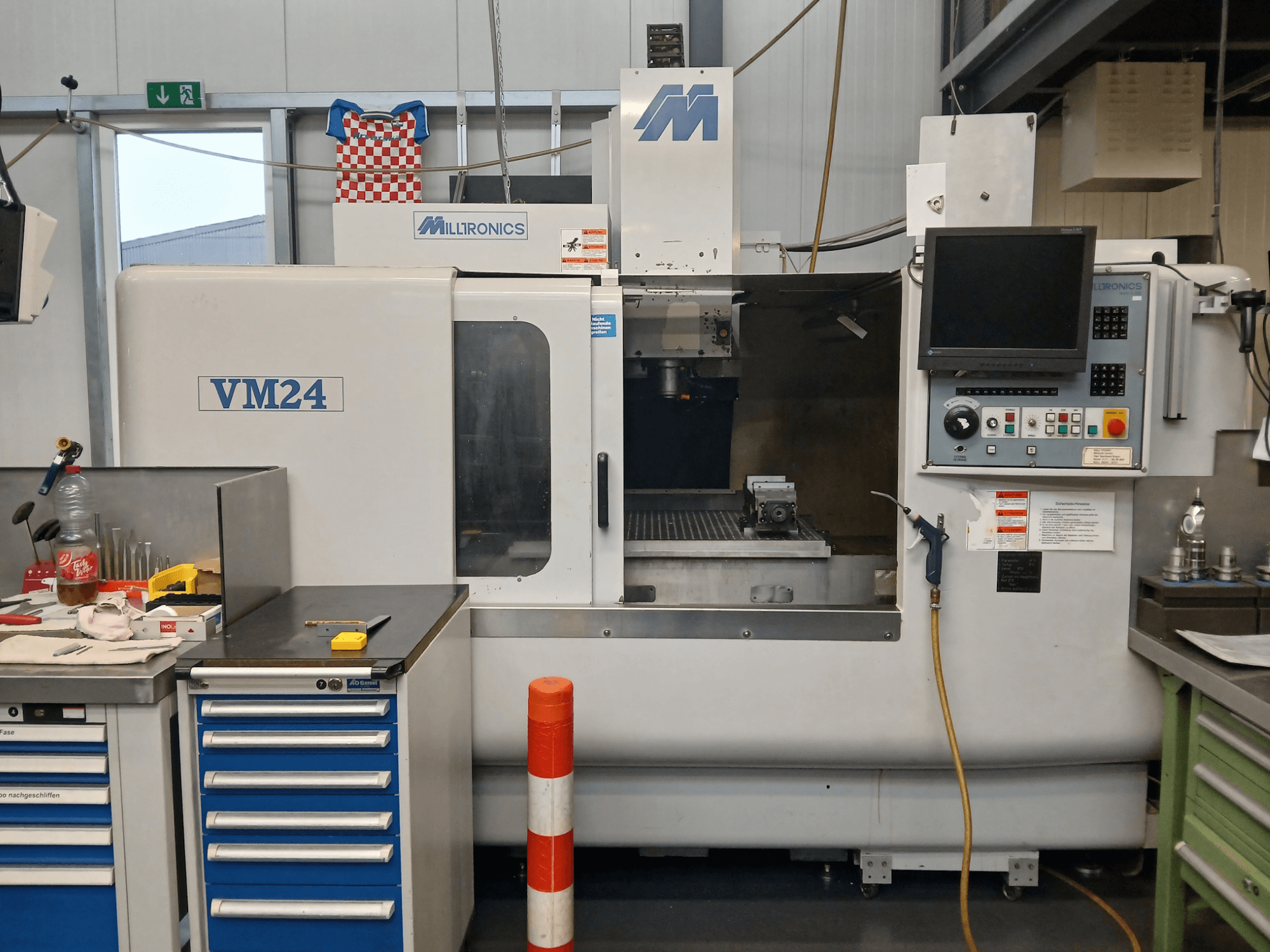 Frezarka CNC Milltronics VM24 pokazana od przodu, z panelem sterowania, magazynem narzędzi i konfiguracją obszaru roboczego.