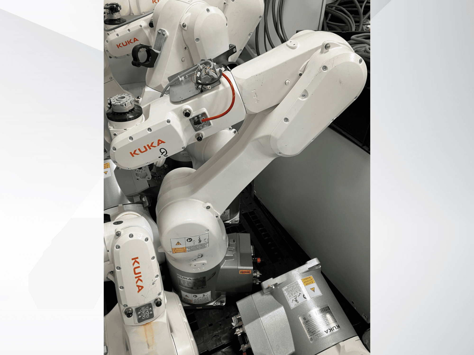 Ramię robota KUKA KR 6 R900 CR, widok z boku; widoczne silniki i złącza, ostrzeżenia bezpieczeństwa i mechaniczne ramiona.