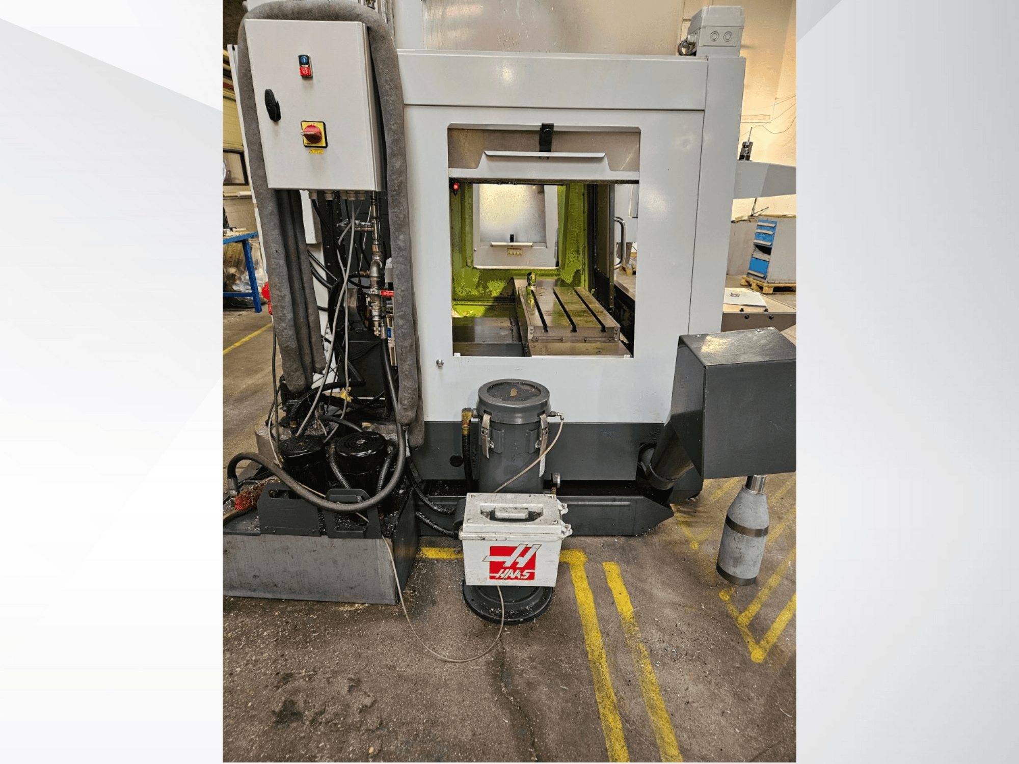 Widok z przodu maszyny CNC Haas przedstawiający panel sterowania, zbiornik chłodziwa i obrobione łoże.