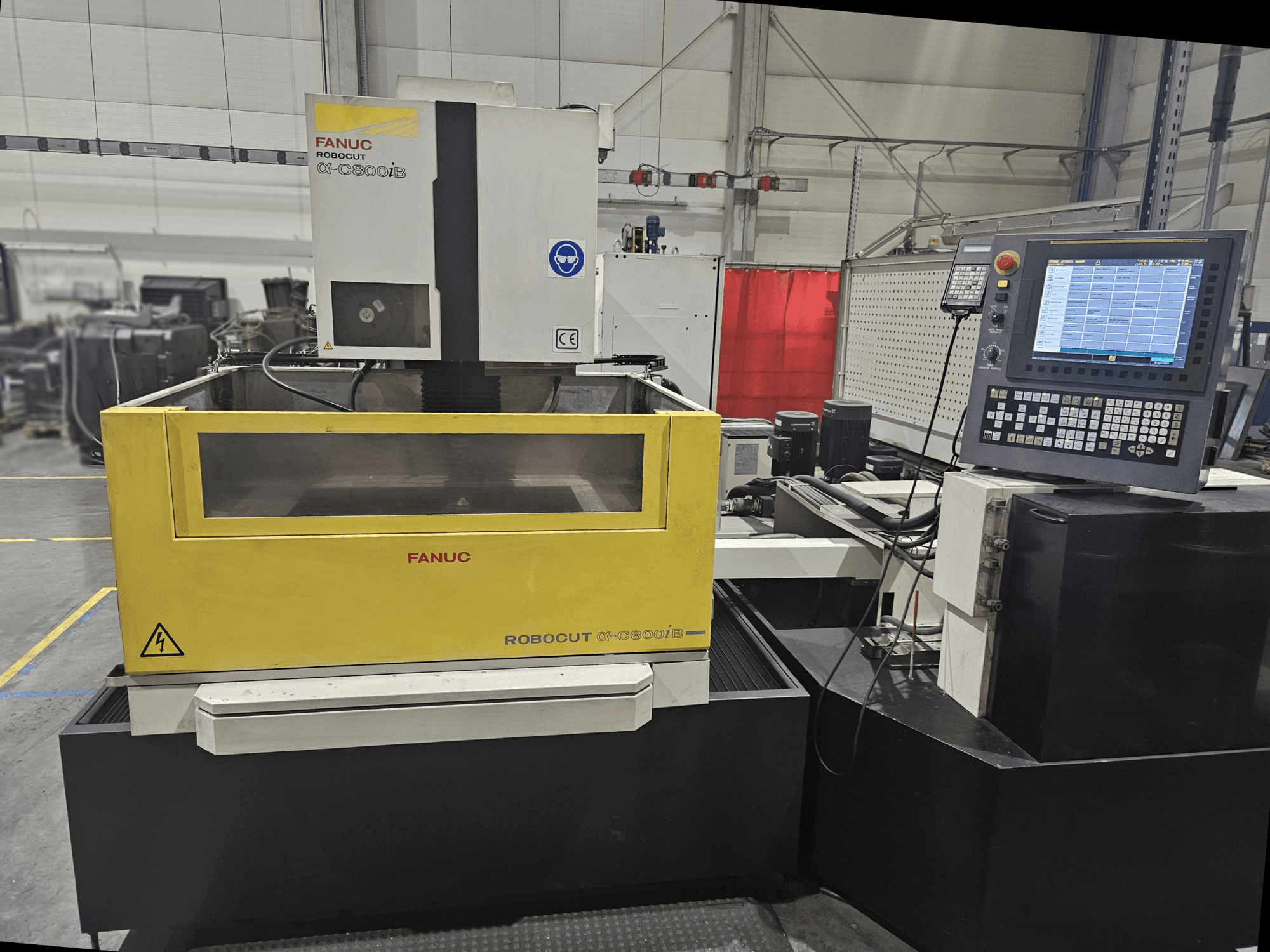 Widok z przodu FANUC Robocut α-C600iB z żółto-szarym korpusem maszyny, panelem sterowania CNC i wyświetlaczem operacyjnym.