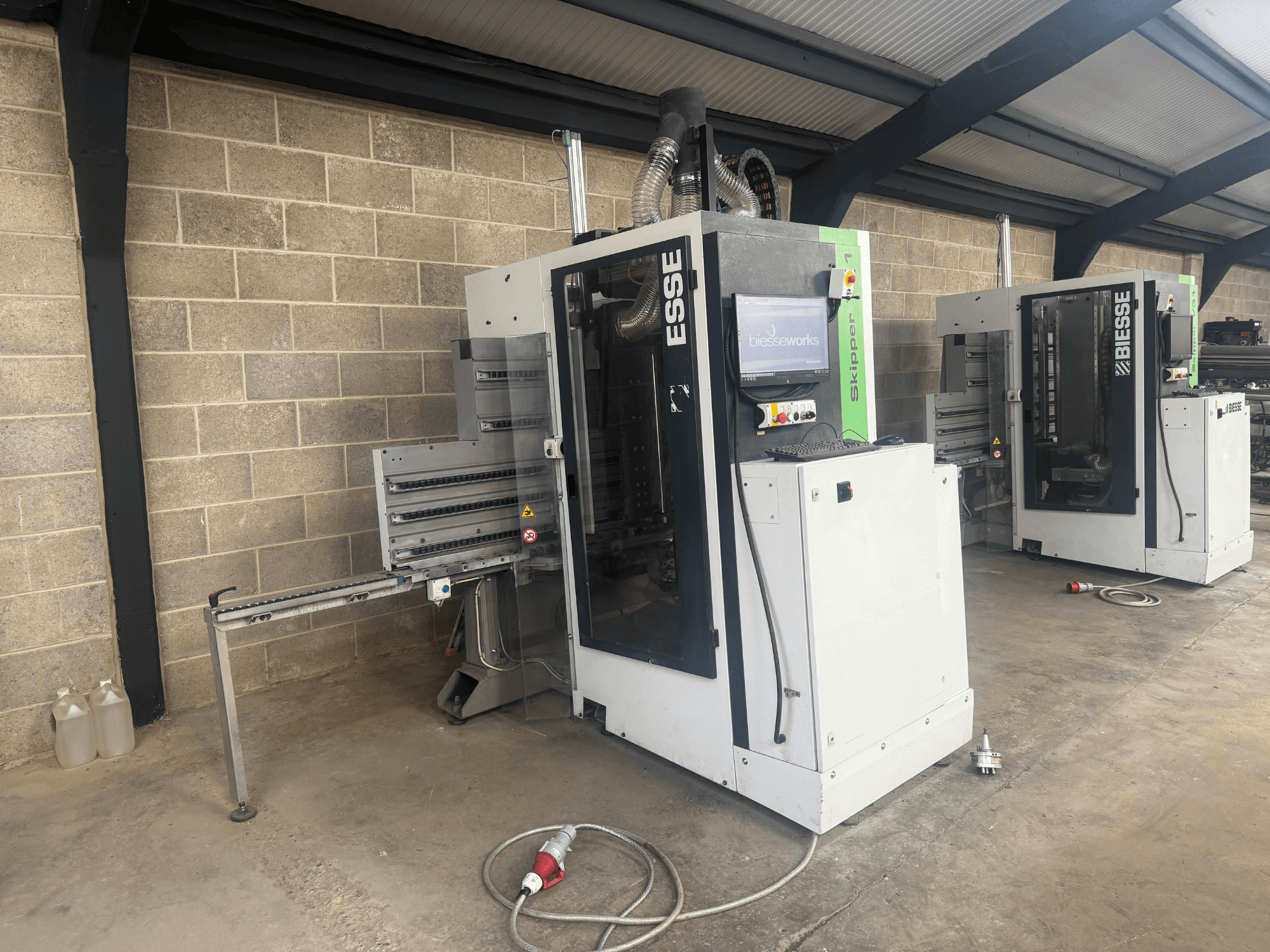 Wytaczarka do drewna BIESSE Skipper v31 w widoku z boku, z panelem sterowania i sąsiednimi maszynami, ustawiona w warsztacie.
