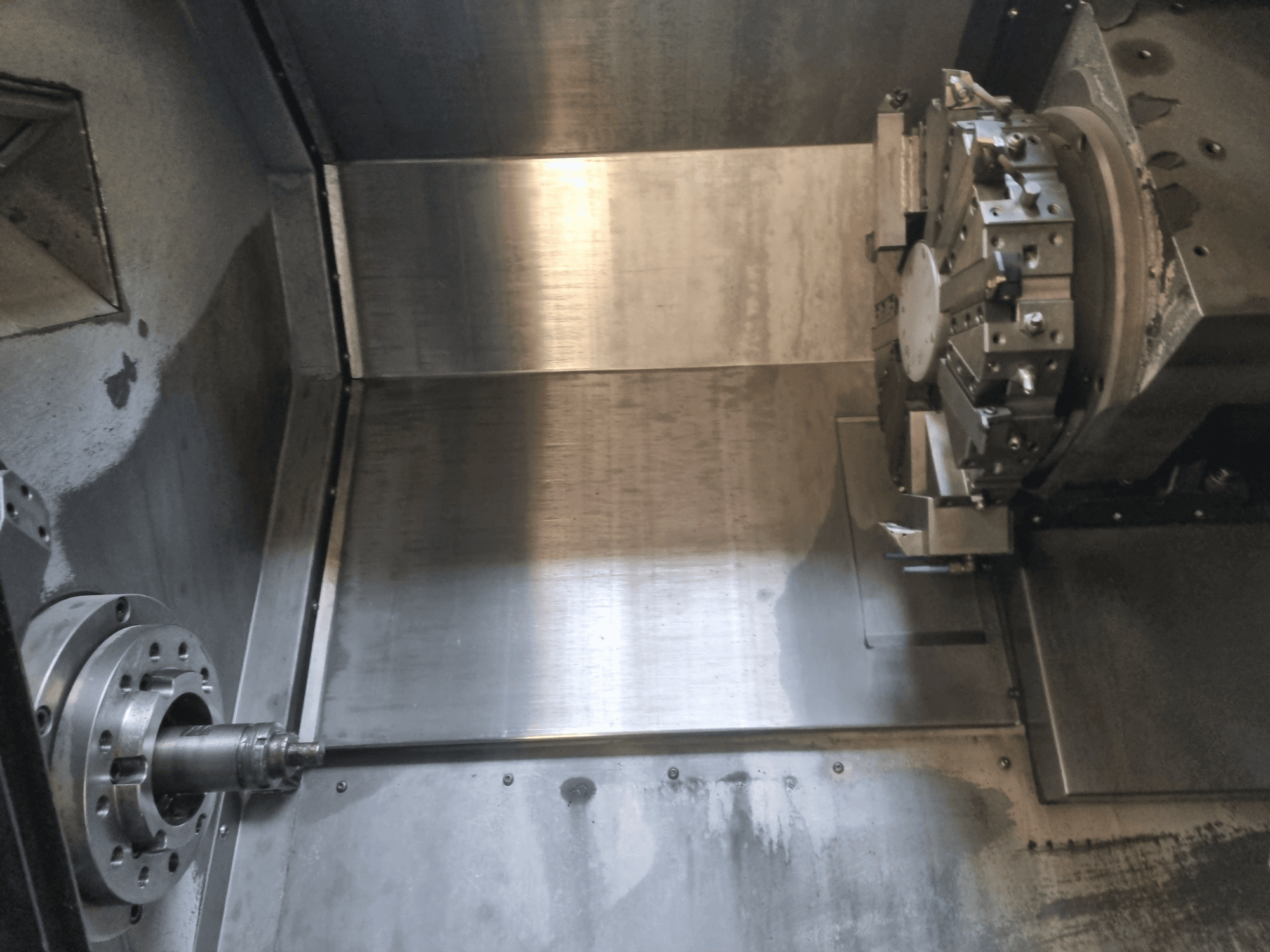 Widok wnętrza tokarki CNC z obracającym się wrzecionem i metalową powierzchnią roboczą, prezentujący precyzyjną inżynierię przemysłową.