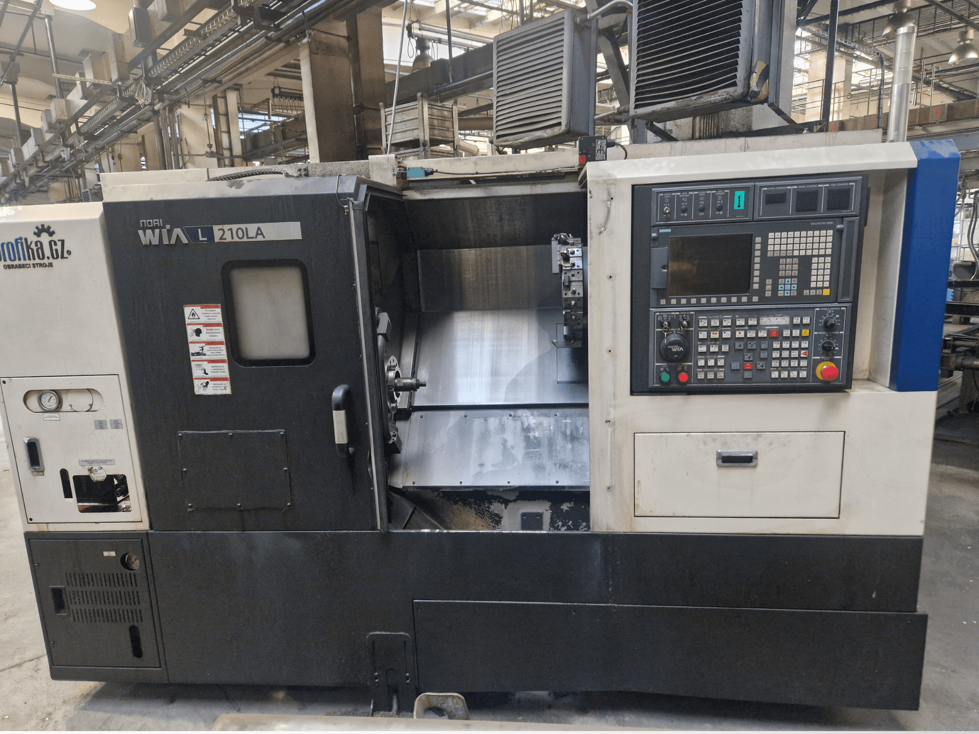 Tokarka CNC WIA L210LA, widok z przodu, posiada panel sterowania z przyciskami, wyświetlaczem i widocznym obszarem obróbki.