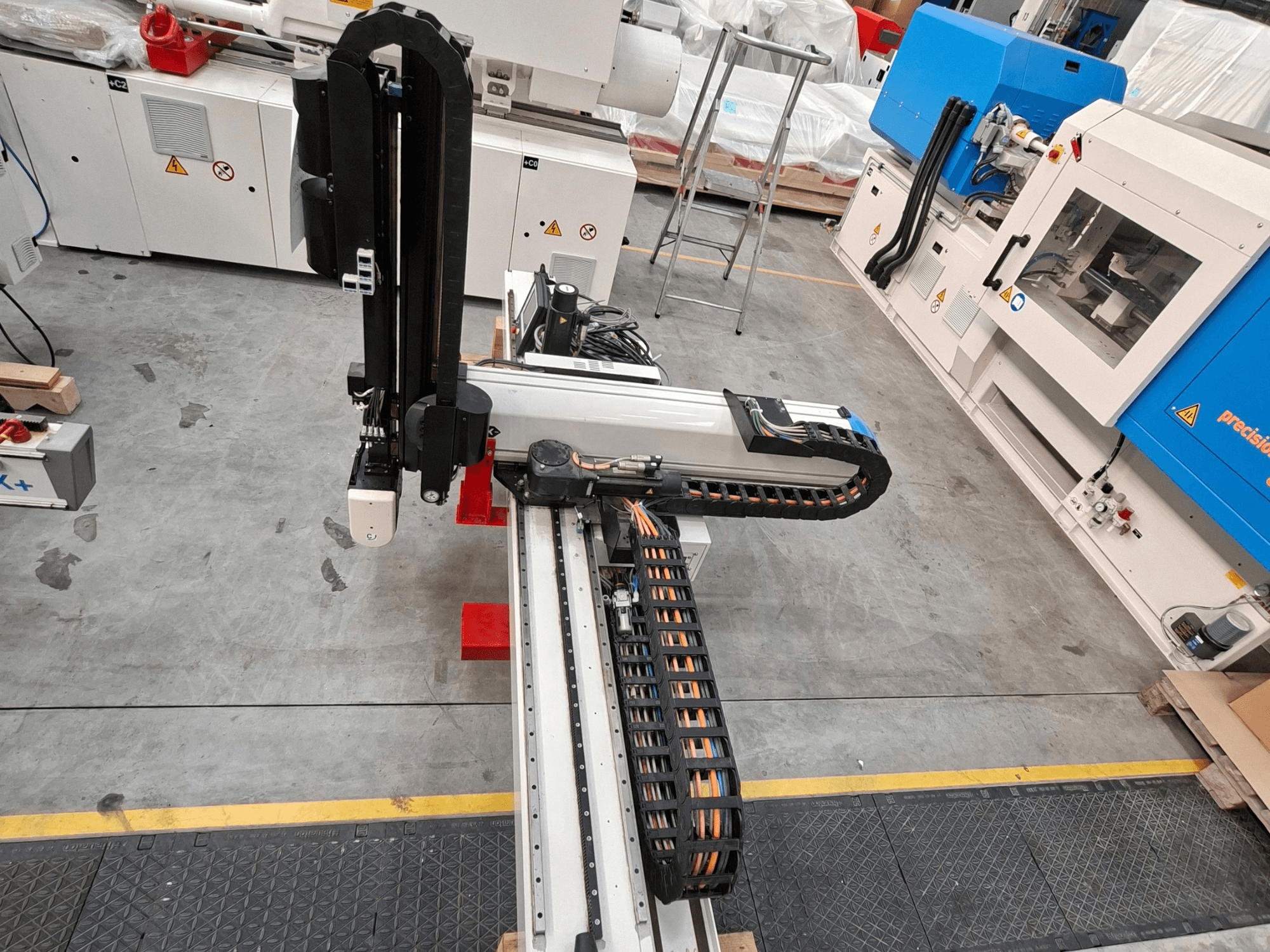 Maszyna do przetwórstwa tworzyw sztucznych Krauss Maffei LRX150-MC5 widziana z góry, z widocznym ramieniem robota i prowadnicą kabli na hali produkcyjnej.