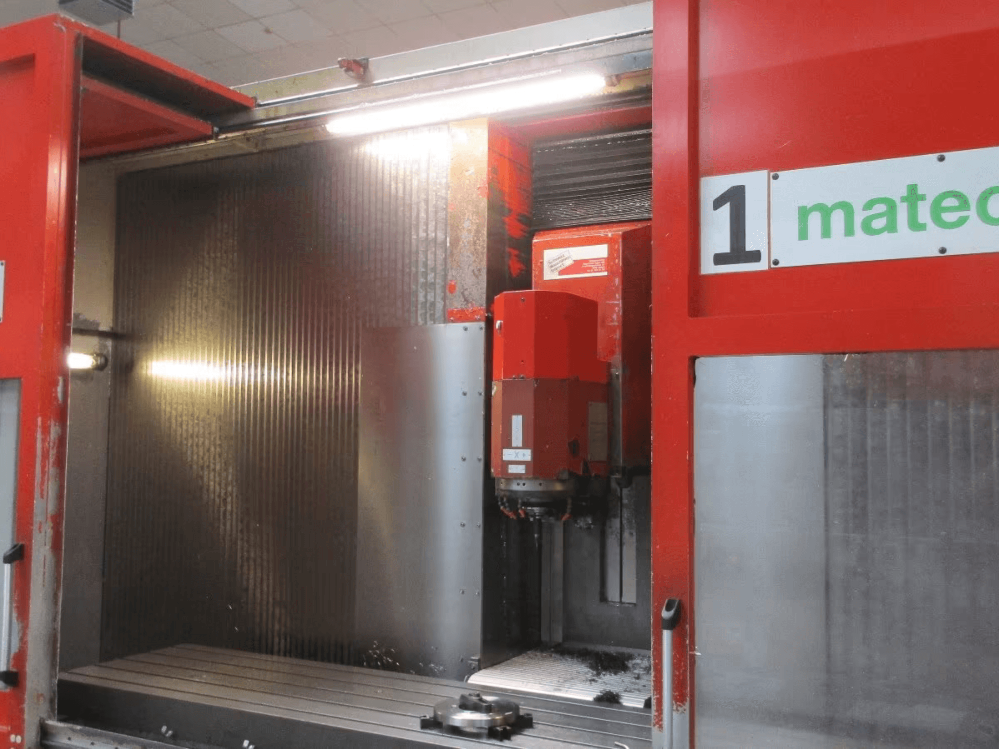 Widok z przodu pionowego centrum obróbczego CNC Matec 30 HV z widocznym narzędziem tnącym, metalową powierzchnią i szczegółami wnętrza maszyny.