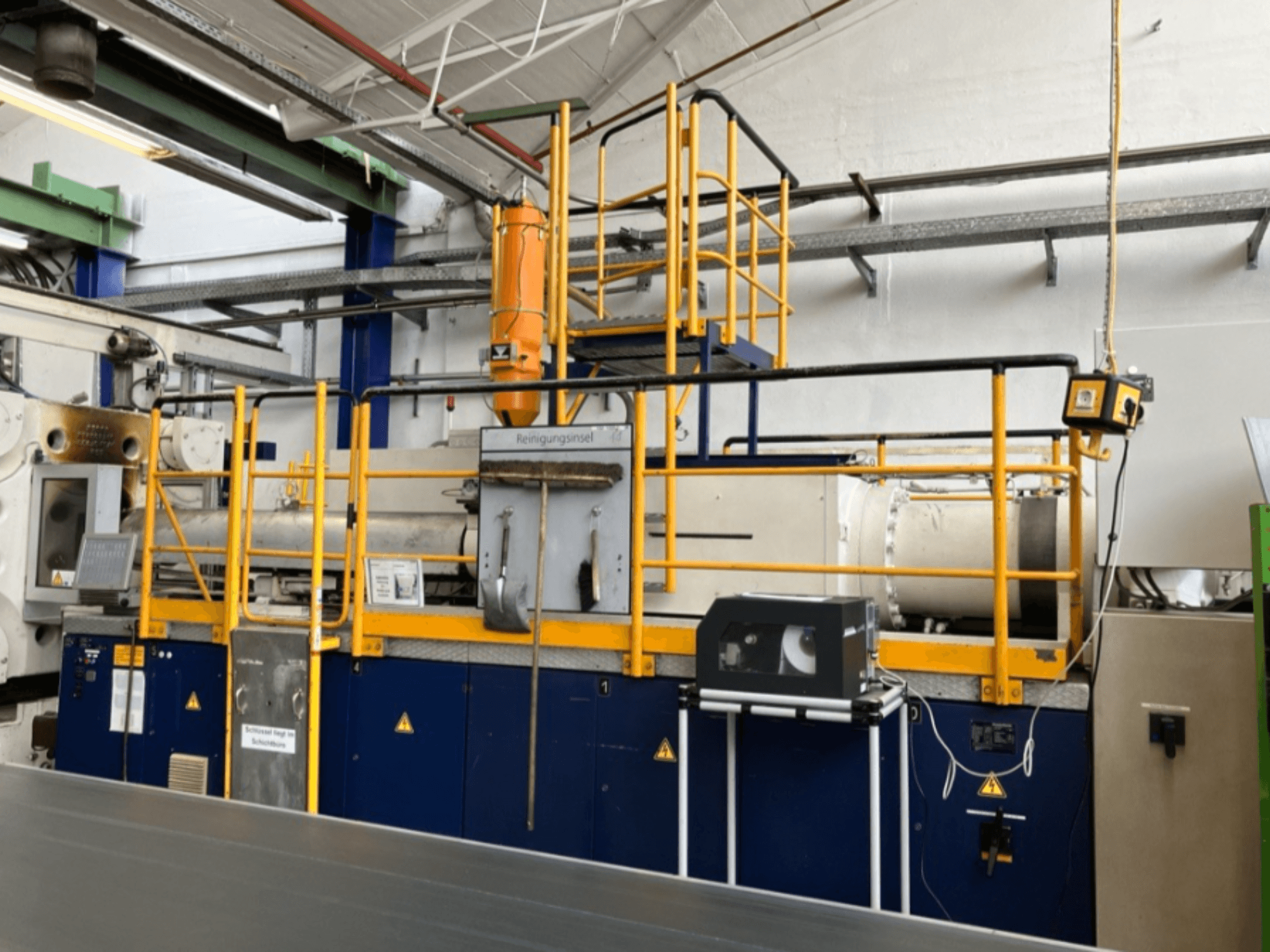 Hydrauliczna wtryskarka Krauss Maffei 1000-8000 M, widok z boku z widoczną barierką ochronną i panelem sterowania.