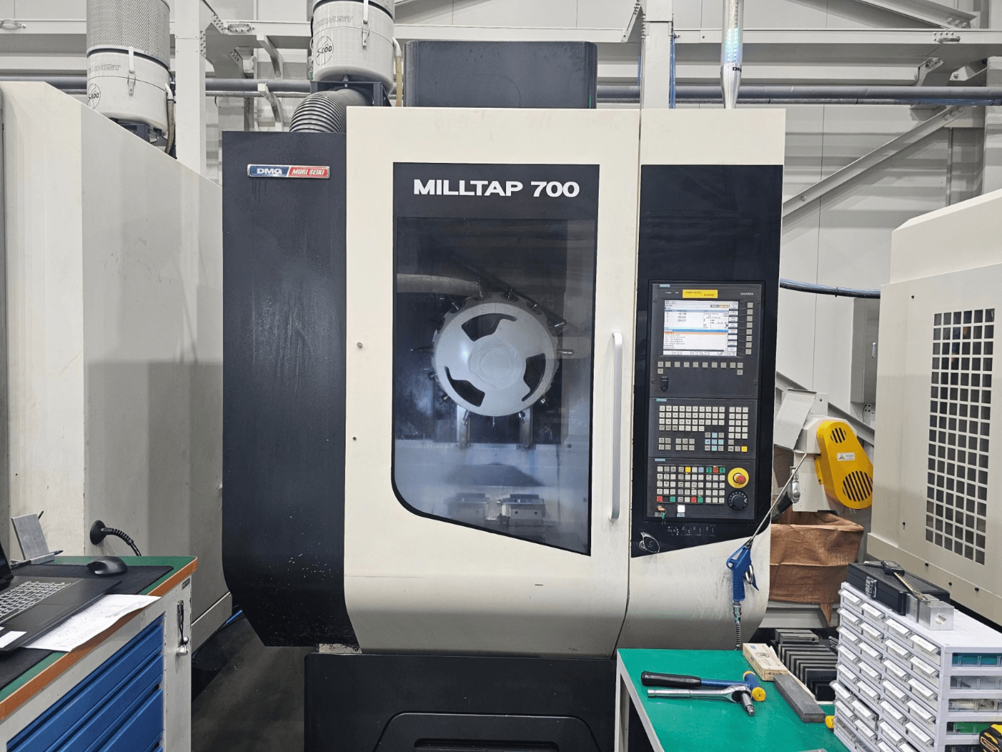 Pionowe centrum obróbcze DMG MORI MILLTAP 700 – widok z przodu, przedstawiający panel sterowania, wrzeciono oraz szczegóły obszaru roboczego.