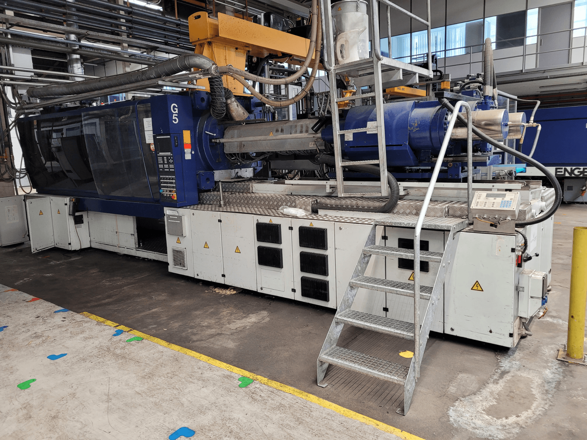 Wtryskarka G5, widok z boku, z widocznym panelem sterowania, drabinką i powierzchnią roboczą ze stali nierdzewnej.