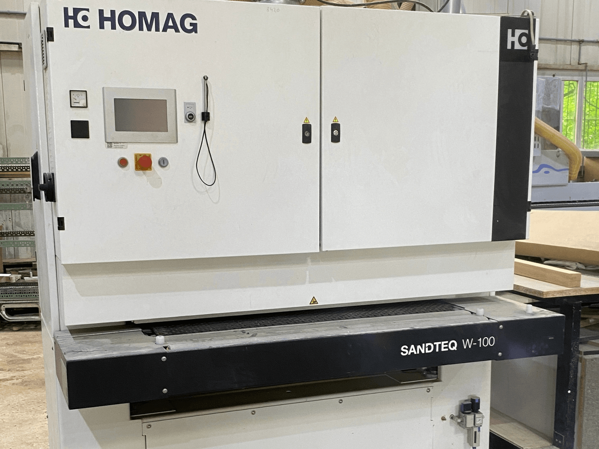 Szlifierka taśmowa HOMAG SANDTEQ W-100 w warsztacie – widoczny jest panel sterowania, przyłącze odpylające oraz obszar taśmy szlifierskiej. Widok z przodu.