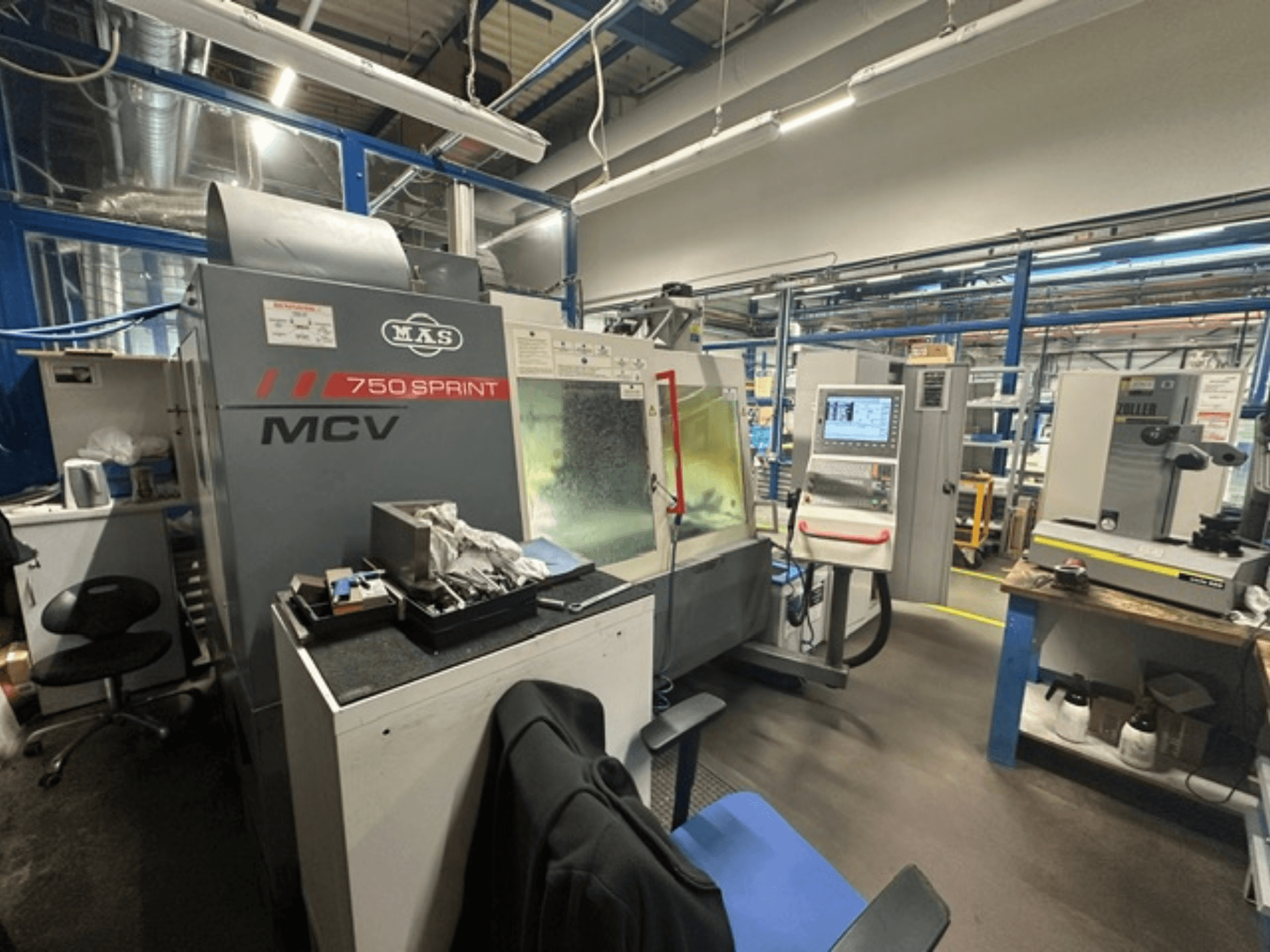 Pionowe centrum obróbcze KOVOSVIT MAS MCV 750 Sprint w warsztacie – widok z boku przedstawiający panel sterowania i obszar roboczy.