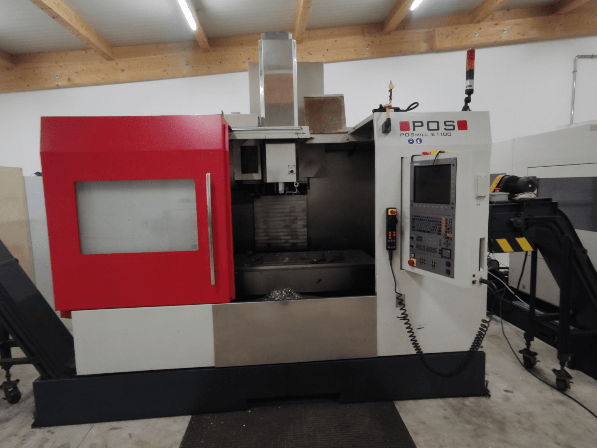 Frezarka CNC POSMILL E1100 w widoku z przodu z czerwoną obudową, panelem sterowania i lampką bezpieczeństwa na górze.