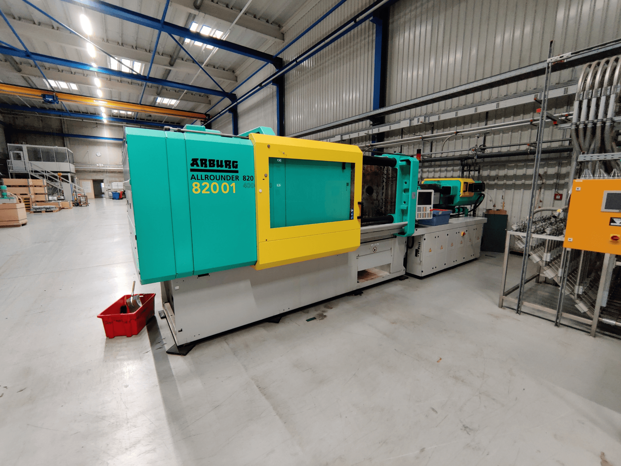 Widok z przodu hydraulicznej wtryskarki Arburg 820 S 4000-2100 z jasnozielonymi i żółtymi panelami.